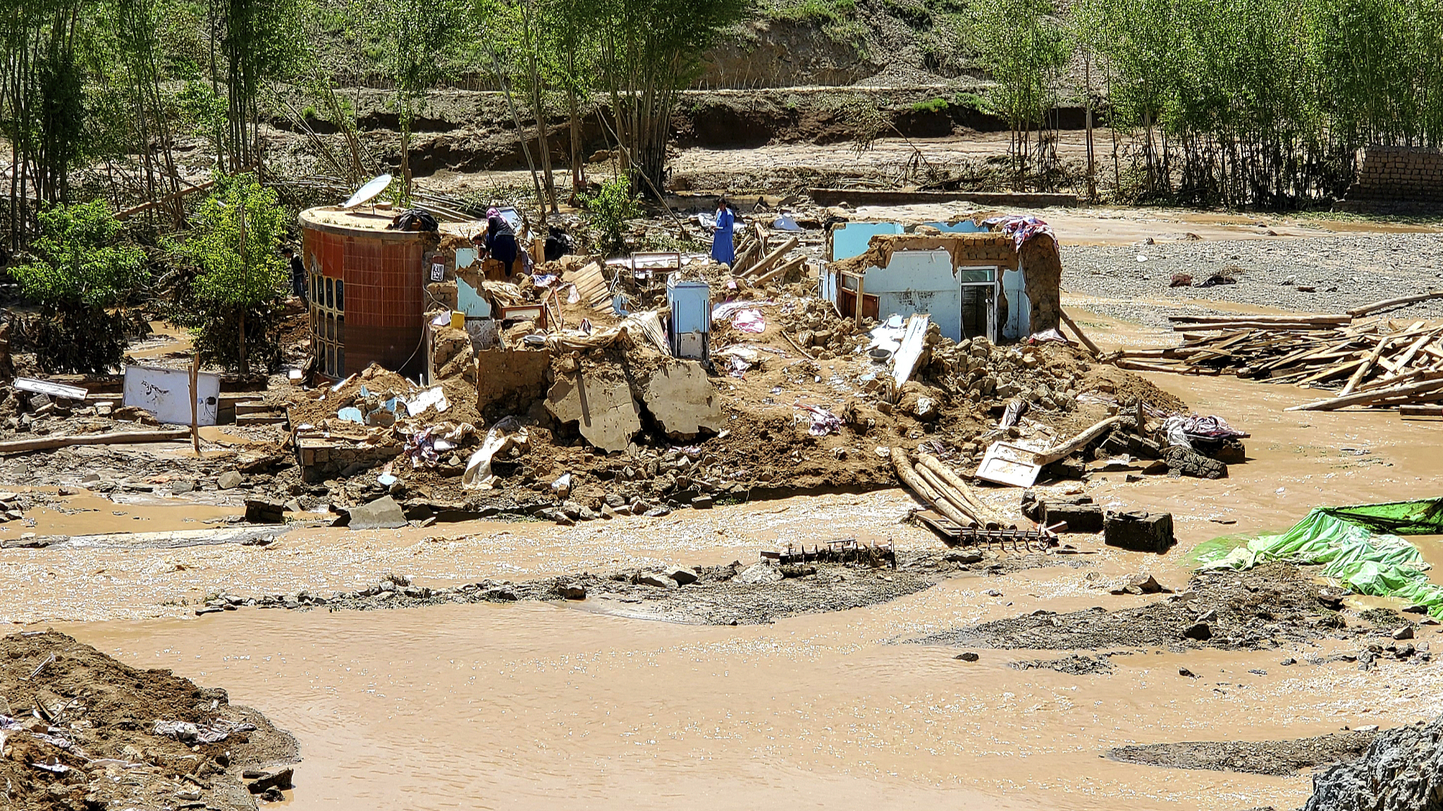 Afghan men collect their belongings from their damaged home after heavy flooding in Ghor province in western Afghanistan, May 18, 2024. /CFP
