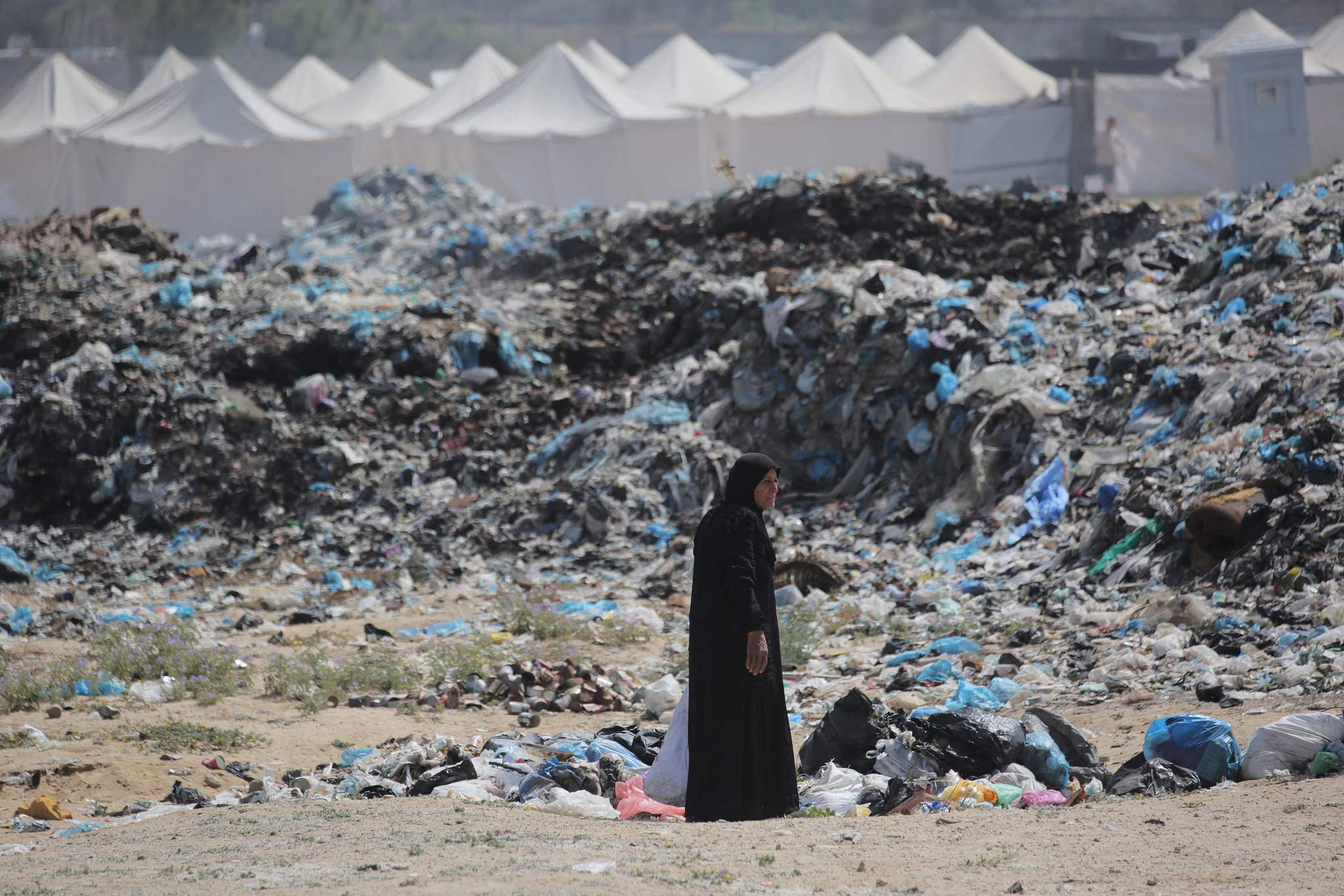 A woman salvages items from a waste dump along a displacement camp west of Nuseirat in the Gaza Strip, May 21, 2024. /CFP