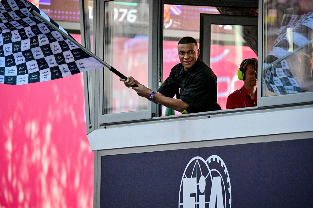 French football star Kylian Mbappe waves the chequered flag at the end of the F1 Grand Prix at the Circuit de Monaco in Monaco, May 26, 2024. /CFP