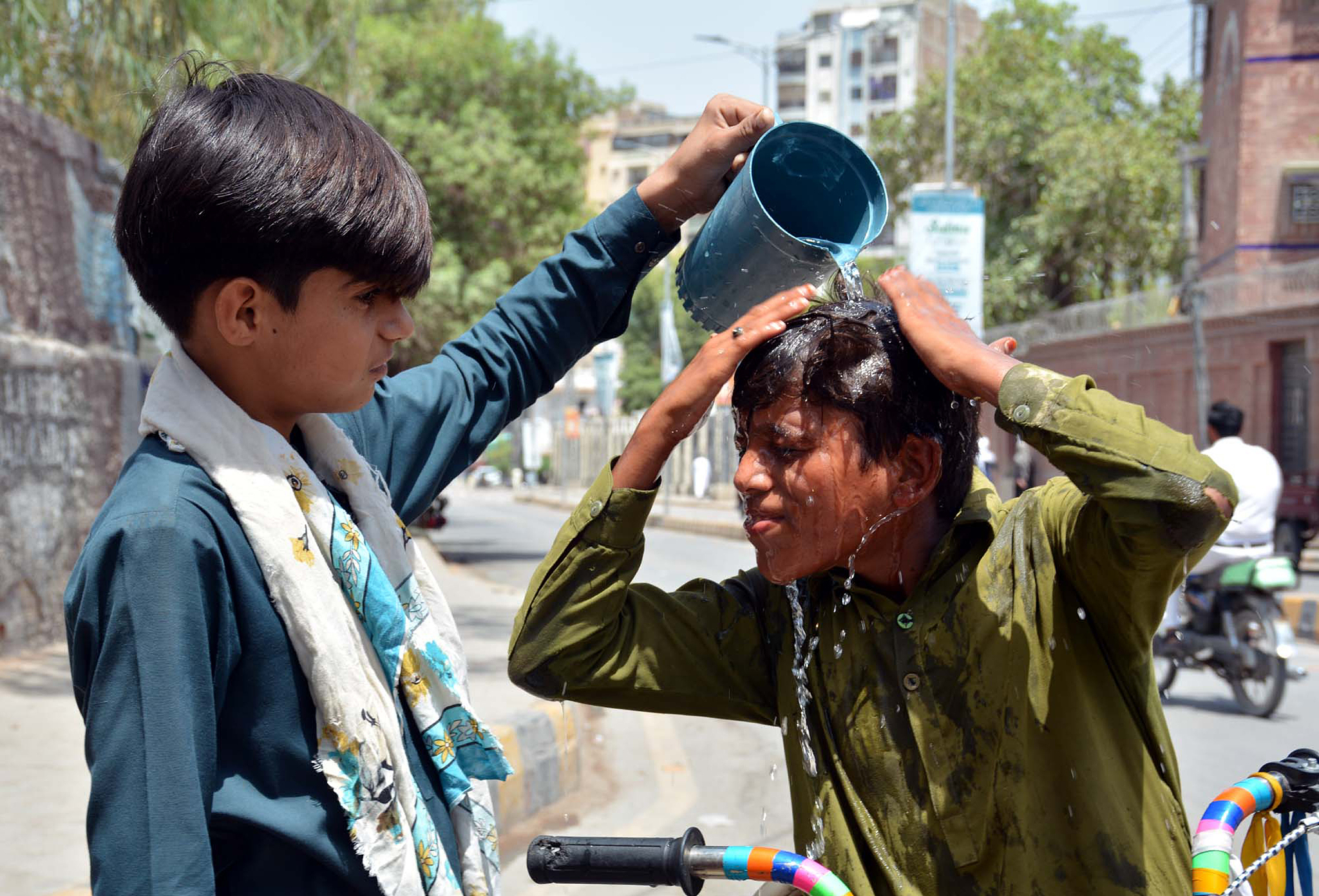 A boy has water poured on his head to cool himself during a hot summer day in Sukkur, Sindh, Pakistan, May 26, 2024. /CFP