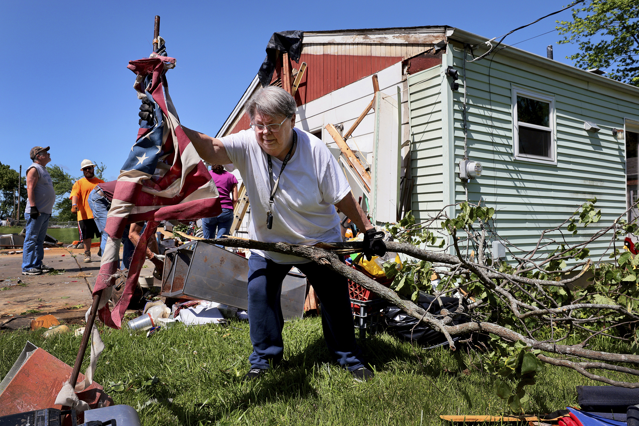 Patti Manley, 69, moves a shredded American flag as she gathers branches from the backyard of her mother's home following a violent storm on Morningdale Place, St. Louis, Missouri, U.S., May 27, 2024. /CFP