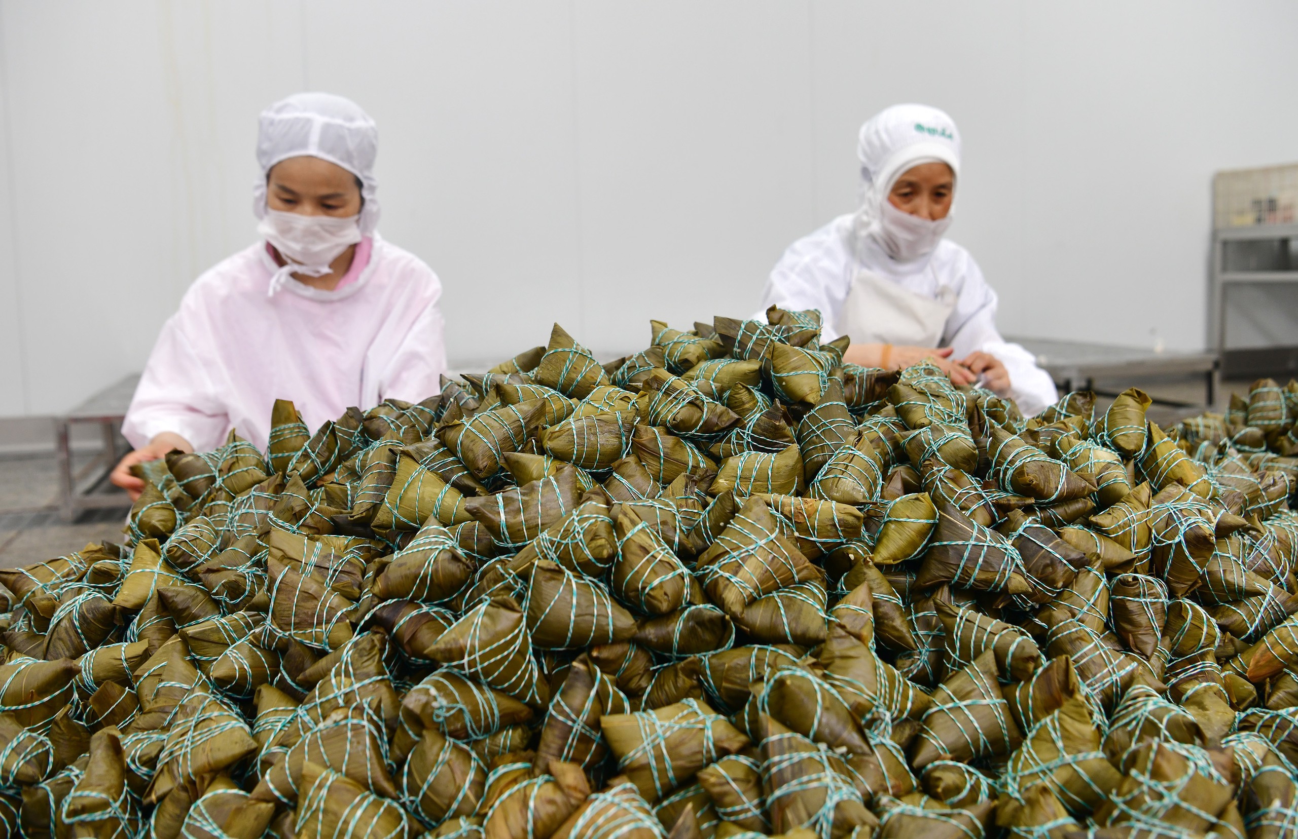 Workers wrap the glutinous rice dumplings known as zongzi at a factory in Zigui County, Hubei Province on May 26, 2024. /IC