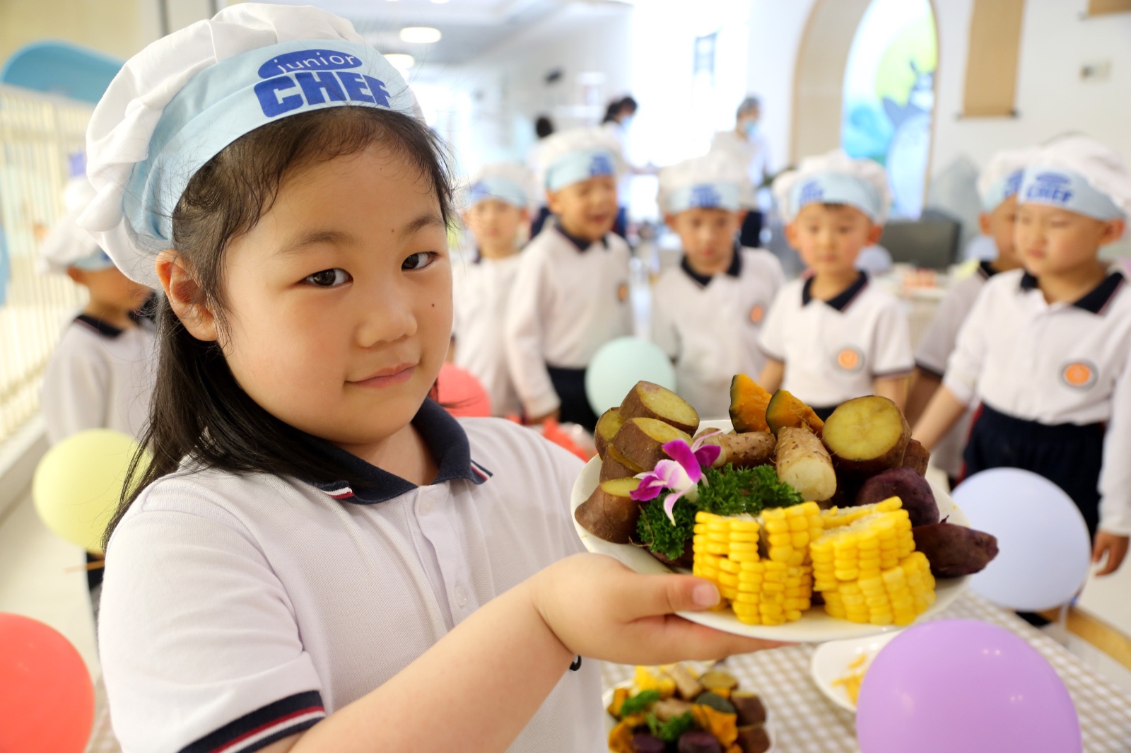 A girl shows off a dish at a food festival held at the affiliated kindergarten of Suzhou Foreign Language School in Lianyungang, Jiangsu Province on May 28, 2024. /IC