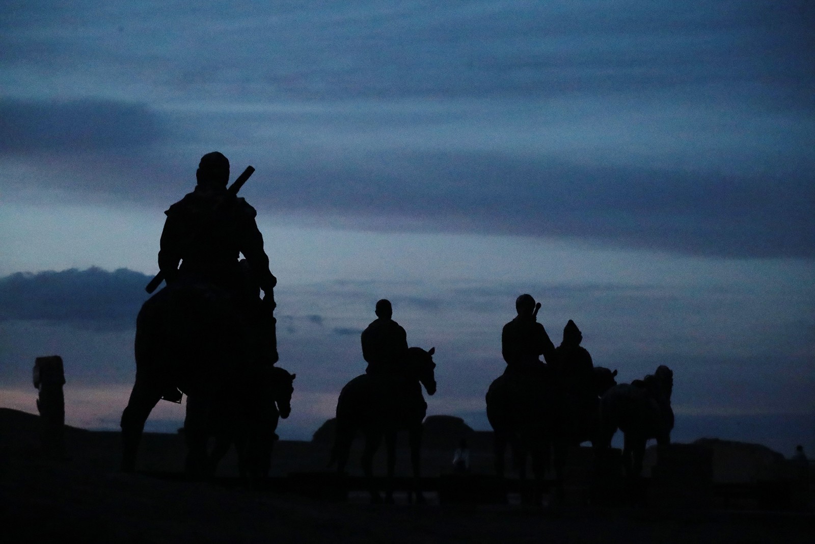 Statues of horse-riders appear lifelike in the evening at the 