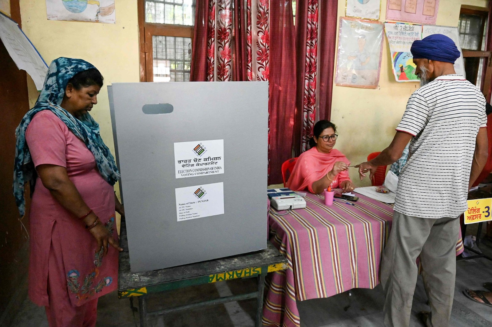 A woman (L) casts her ballot to vote as a polling official (C) applies indelible ink to another voter after he cast his vote at a polling station on the outskirts of Amritsar, India, June 1, 2024. /CFP
