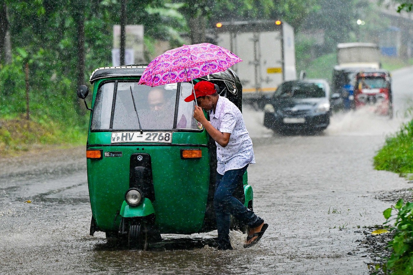 A man pushes an autorickshaw through a flooded street amid heavy rainfall in Malwana on the outskirts of Colombo on June 1, 2024. /CFP