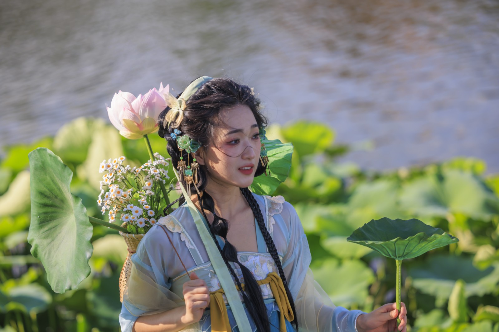 A young woman in traditional hanfu attire poses for photos in front of a lotus pond in Kunming, Yunnan Province, on June 2, 2024. /CFP