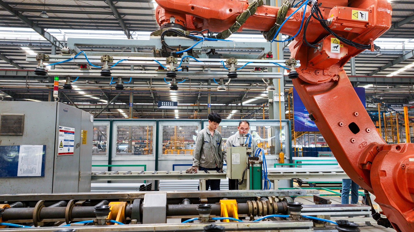 Workers at a company in Huzhou City, Zhejiang Province, operating an intelligent robotic arm production line for overseas shipment orders on May 29. / CFP