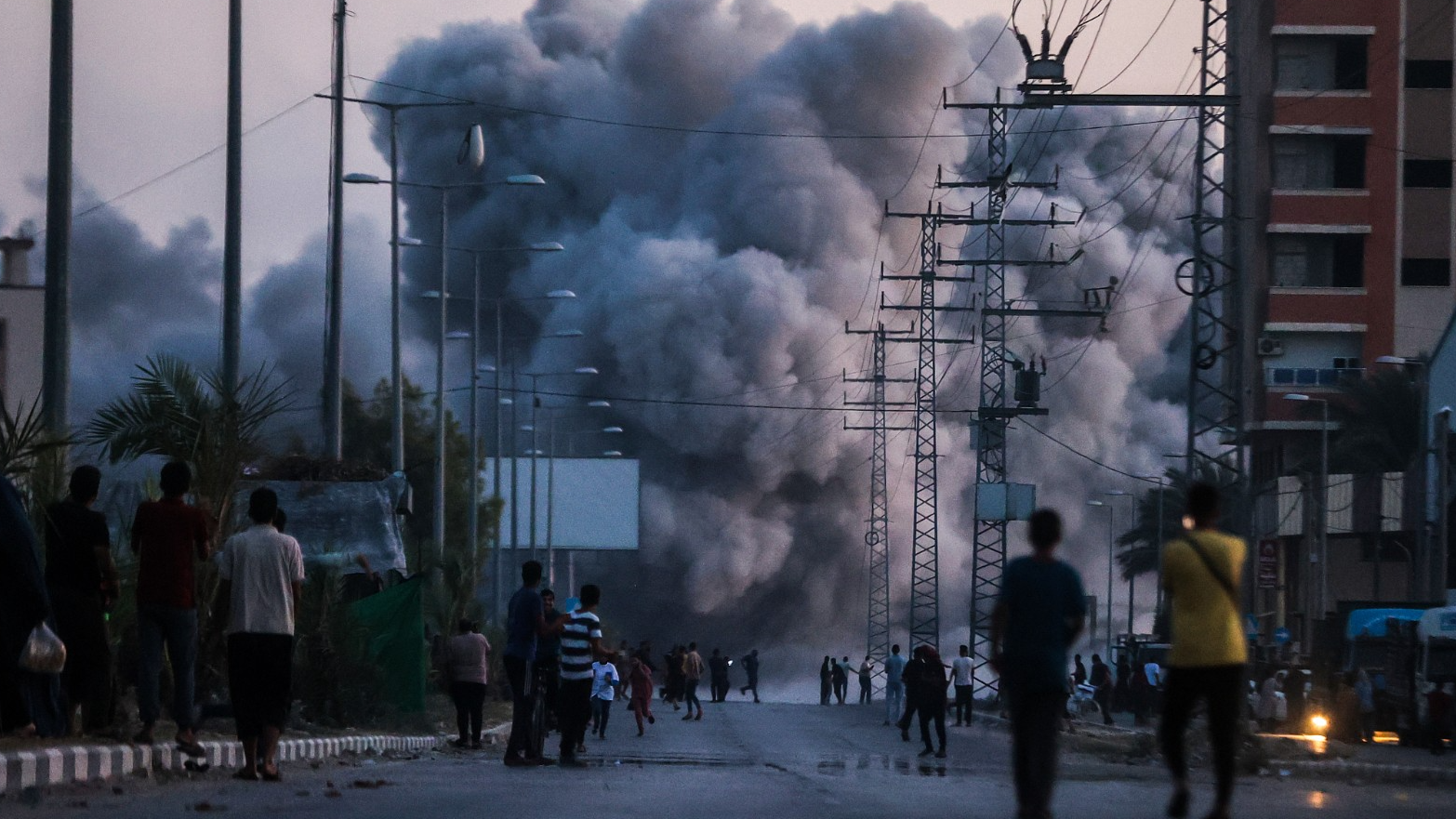 Palestinians stand on a road as black smoke rises over a building following Israeli attacks in Deir al-Balah, Gaza, June 6, 2024. /CFP