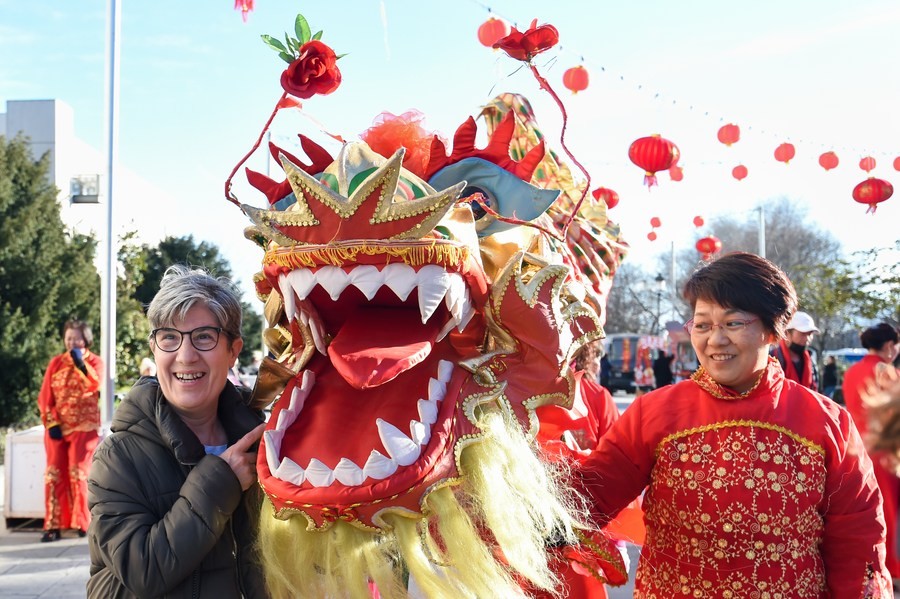 A resident poses for a photo with a lion dancer during an event to celebrate the Chinese New Year in Madrid, Spain, January 20, 2023. /Xinhua