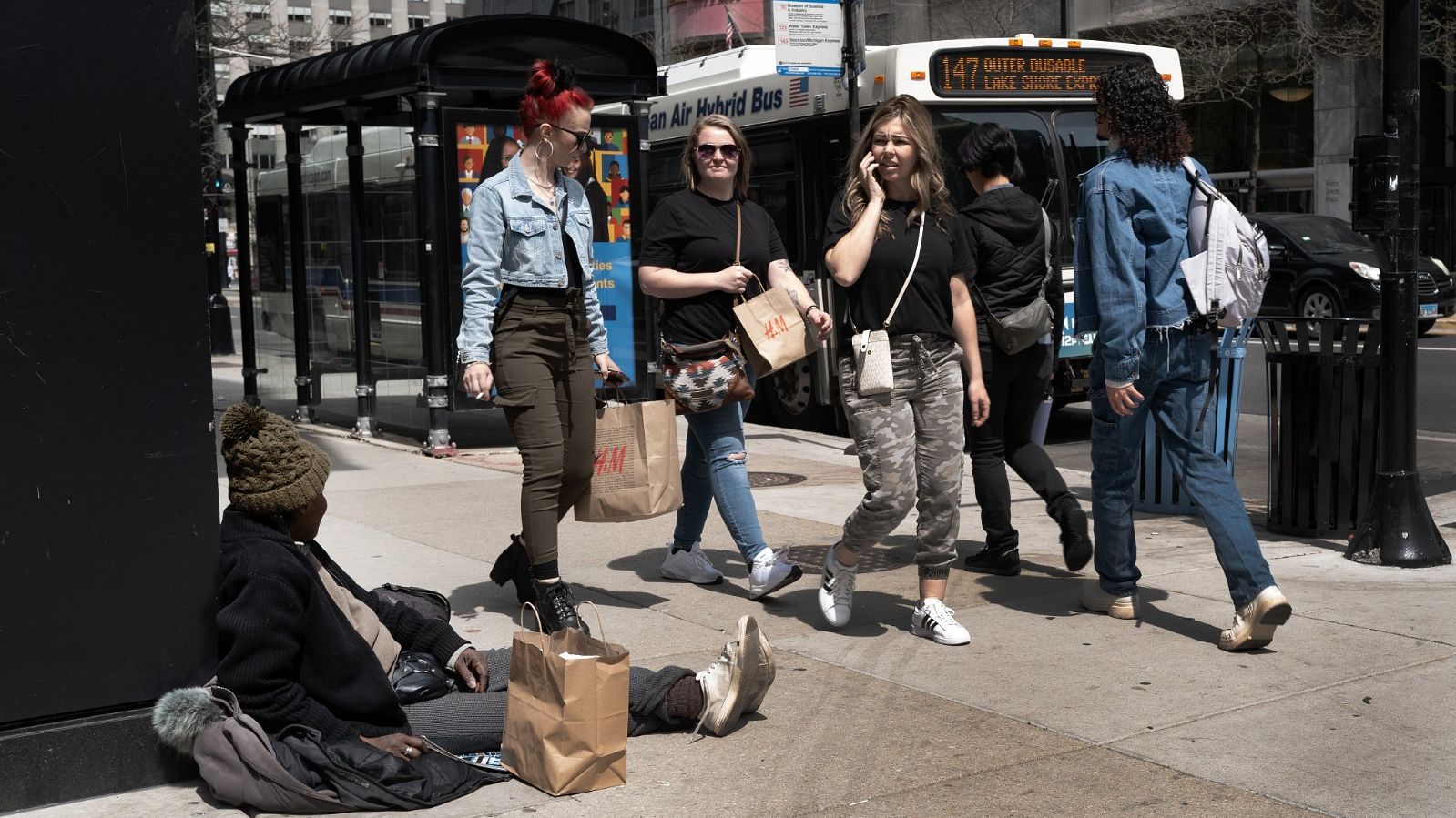 People walk past a woman selling Streetwise, a magazine sold by homeless people or those at risk of becoming homeless, in downtown Chicago, Illinois, U.S., April 22, 2024. /CFP