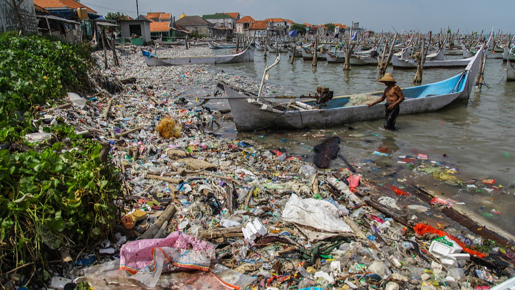 A fisherman arrives at a beach full of rubbish in the Kwanyar district, Bangkalan, Madura Island of Indonesia, May 13, 2024. /CFP