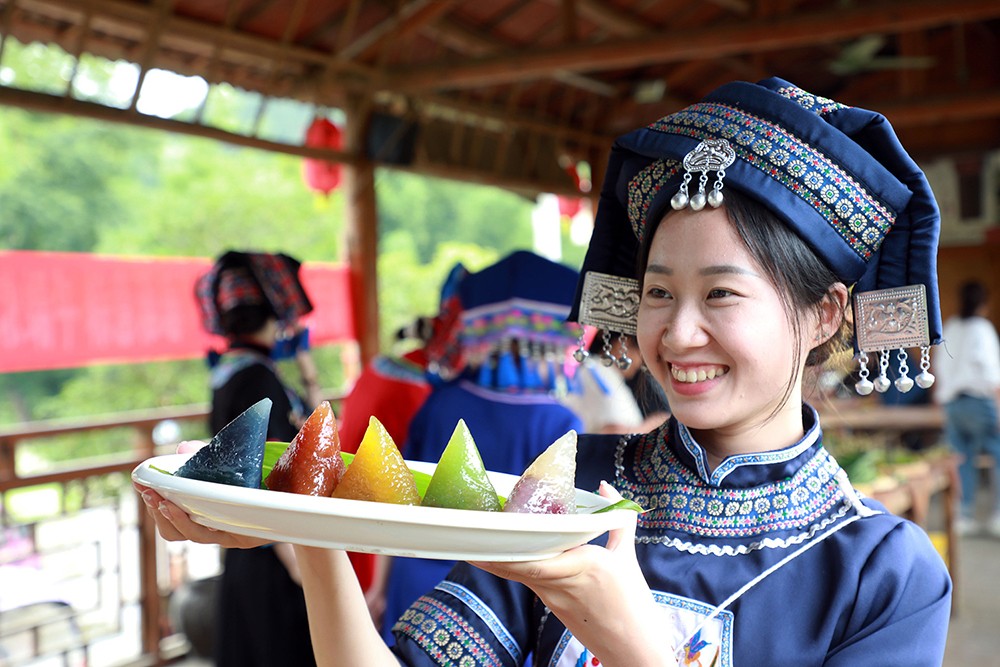 A woman from the Zhuang ethnic group displays a plate of zongzi in five different colors in Liuzhou, Guangxi Zhuang Autonomous Region. /VCG