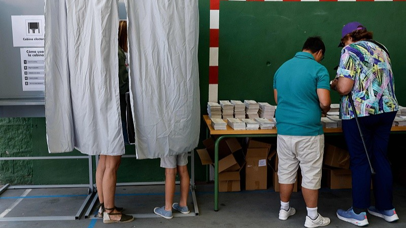 Voters stand in a booth and pick their ballots for the European Parliament elections at a polling station in Madrid, Spain, June 9, 2024. /CFP