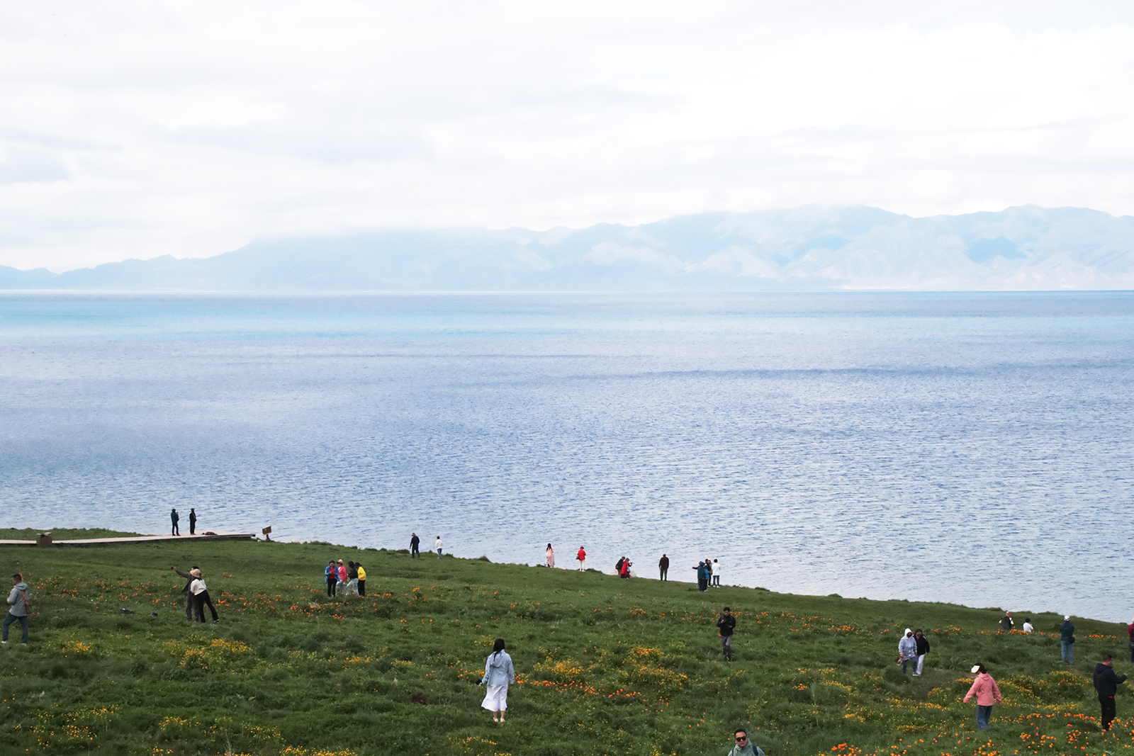 Visitors take photos by Sayram Lake in Xinjiang. /CGTN
