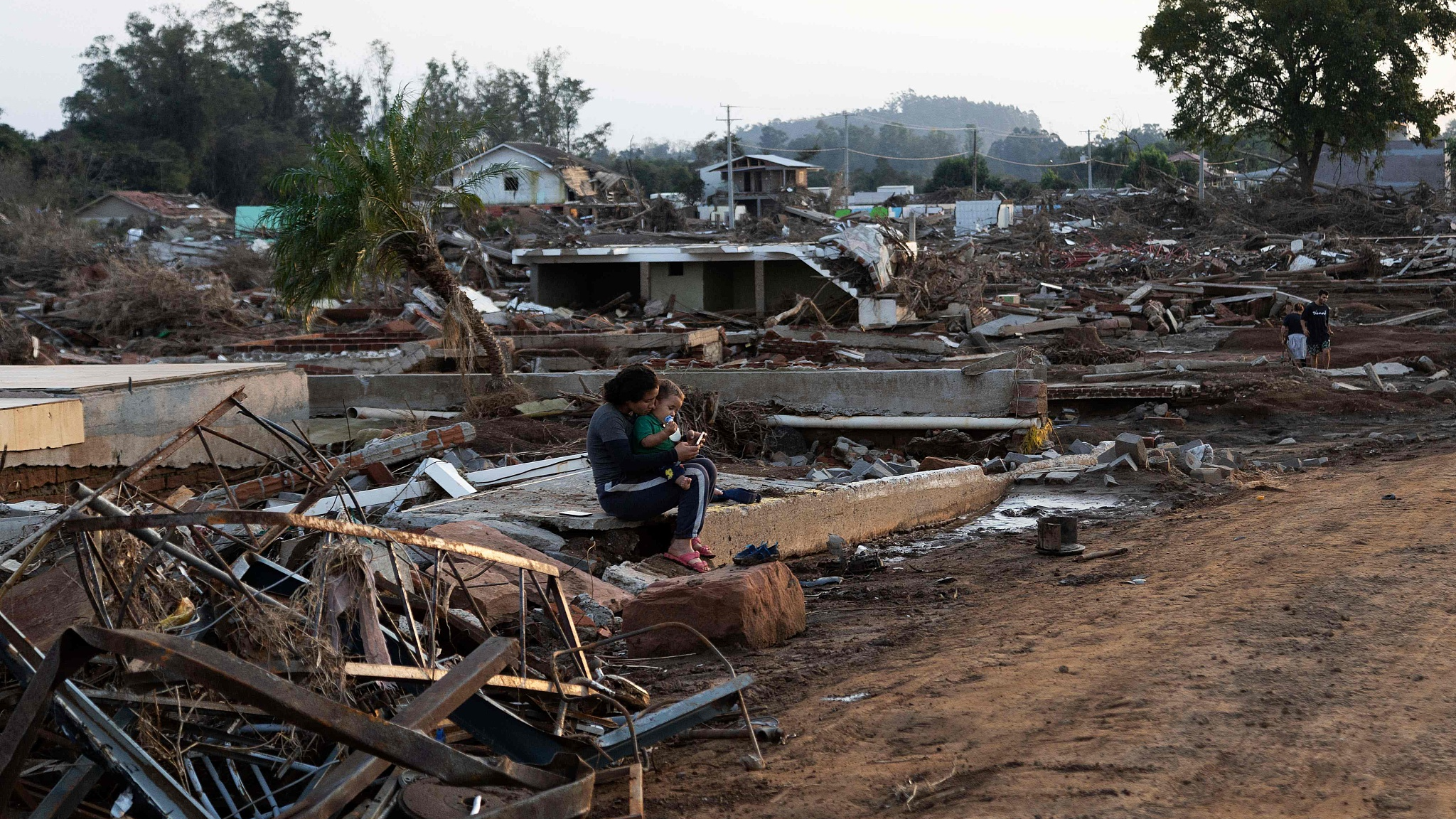 A woman sits with her baby among destroyed houses in the Passo de Estrela neighborhood in Cruzeiro do Sul, Rio Grande do Sul State, Brazil, June 5, 2024. /CFP