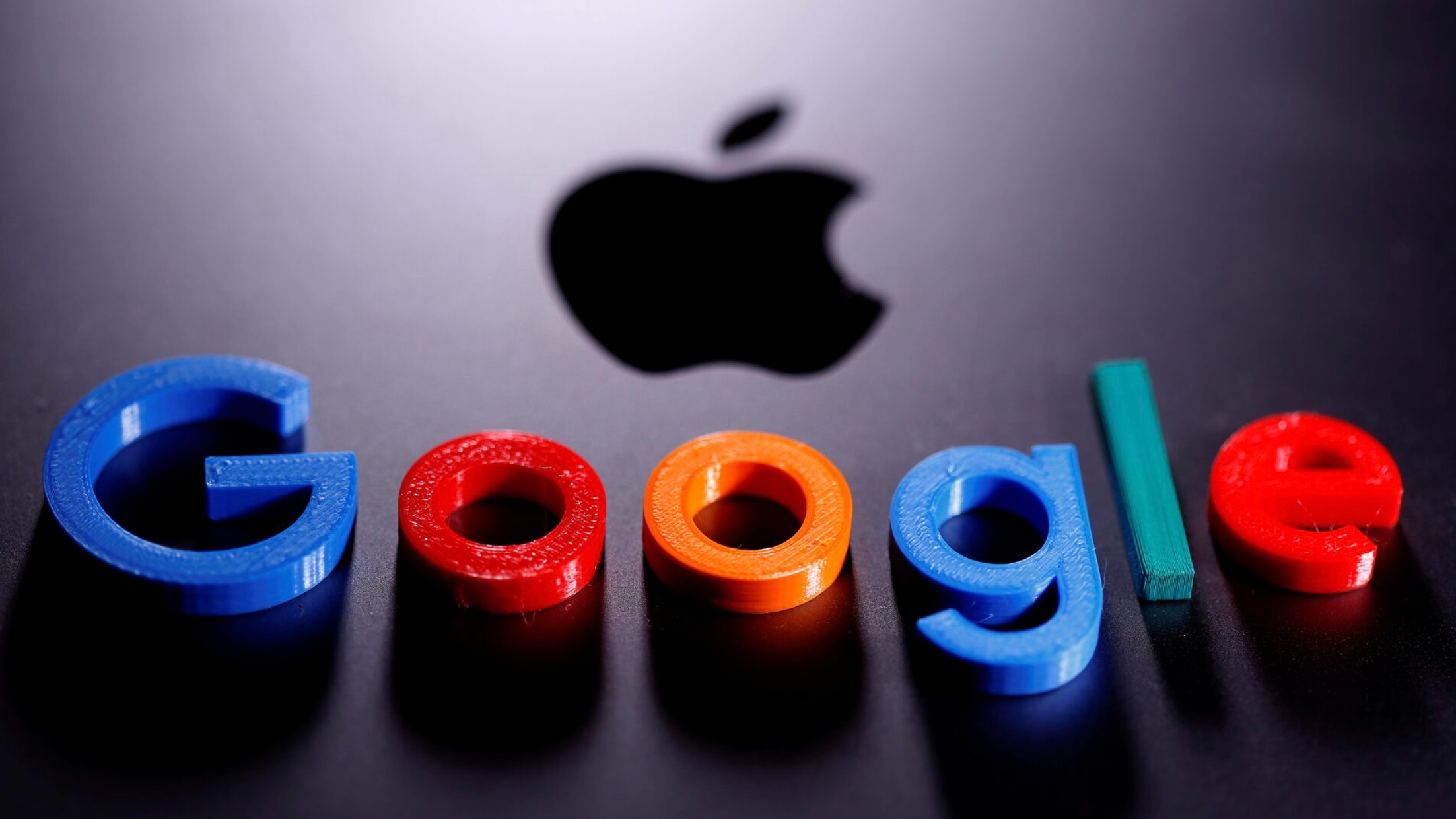 An illustration shows a 3D printed Google logo placed on the Apple Macbook. /Reuters