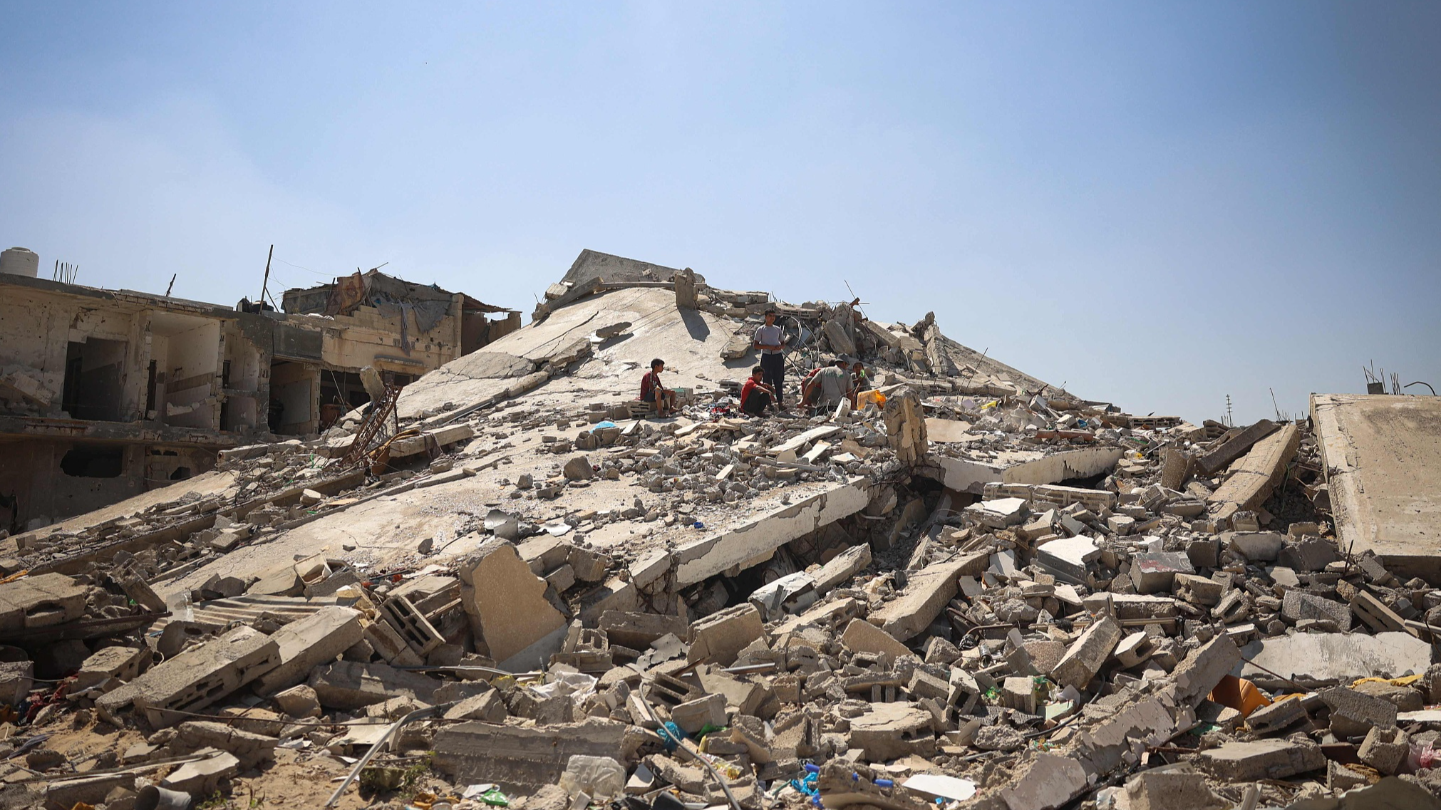 Men sit on the the debris of a building destroyed during the Israeli bombardment of Khan Yunis, in the southern Gaza Strip, June 11, 2024. /CFP