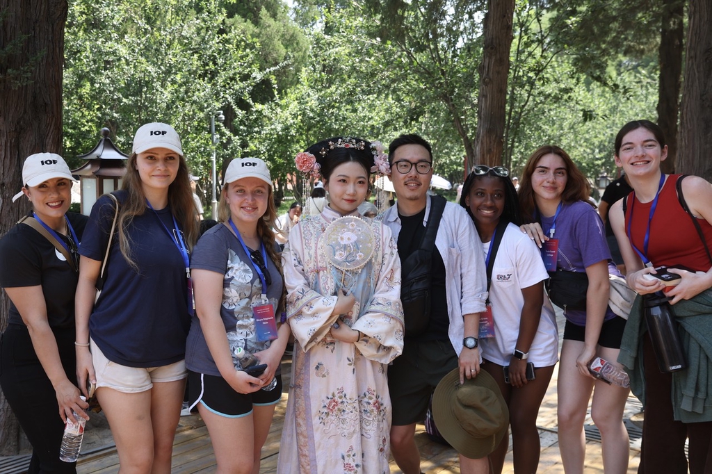A photo taken on June 11, 2024 shows students and teachers from the U.S. state of Iowa taking a photo with a Chinese tourist dressed in traditional attire at the Palace Museum in Beijing, China. /IC