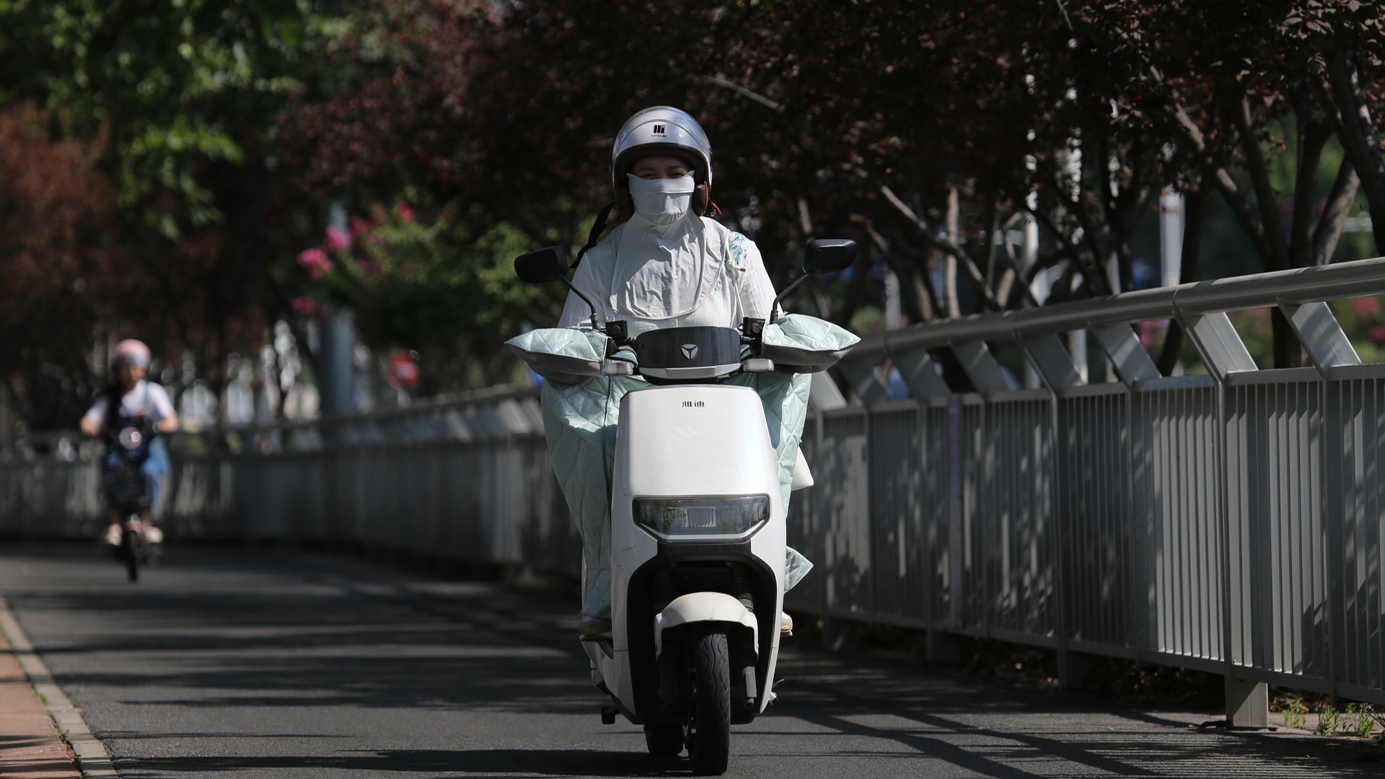 A woman wearing protective fabric over her body and face rides a bike on the street in Zhengzhou, Henan Province, China, June 12, 2024. /CFP