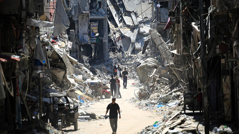 Palestinian men walk by destroyed buildings in Khan Yunis, southern Gaza Strip, June 11, 2024. /CFP