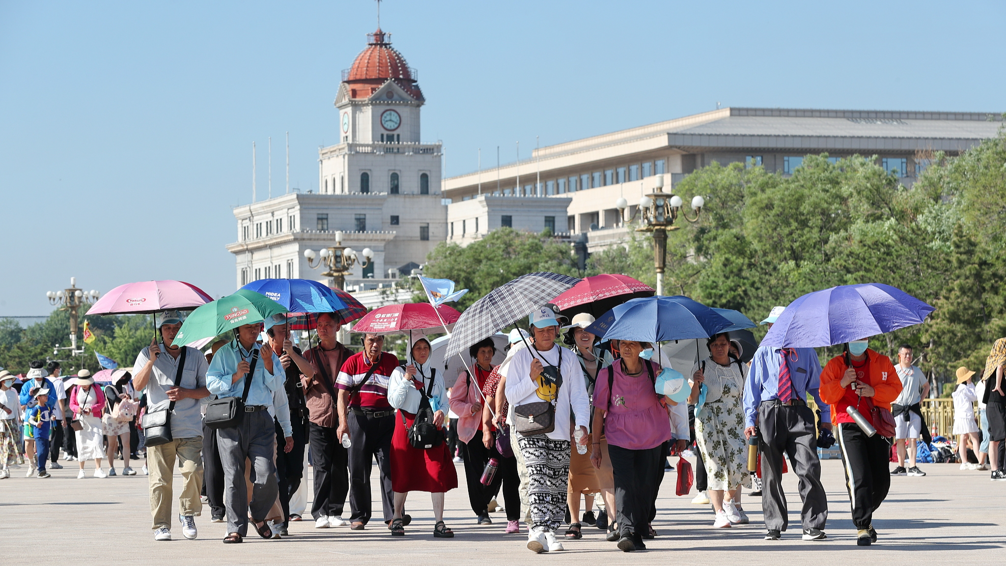 Tourists visit Tiananmen Square while holding up umbrellas to protect themselves from sunshine in Beijing, China, June 15, 2024. /CFP