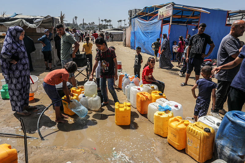 Palestinians queue up to receive clean drinking water distributed by aid organizations in Deir Al-Balah, Gaza, June 10, 2024. /CFP