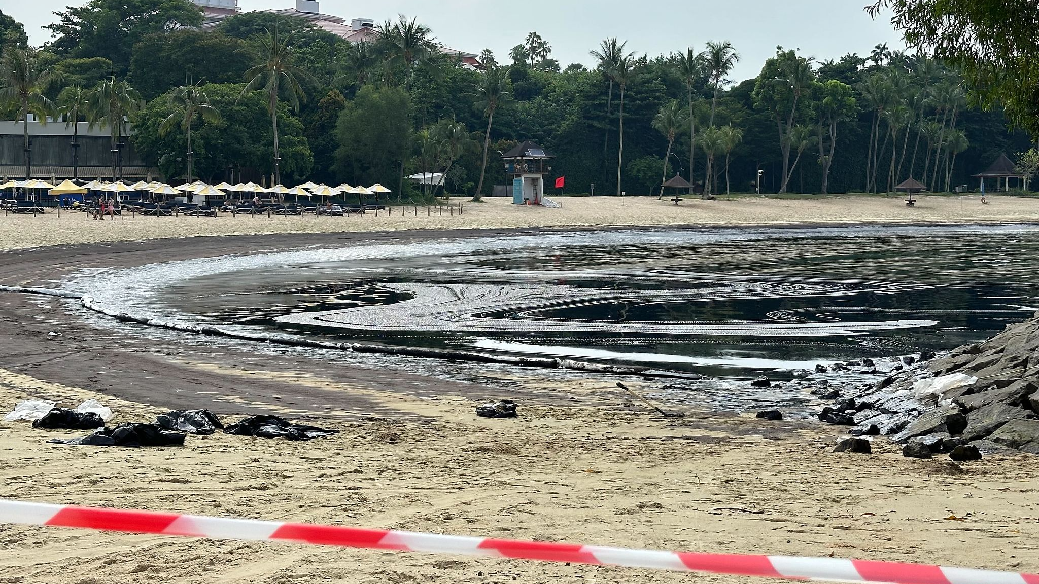 Caution tape near oil-coated sand and rocks along the Tanjong Beach on Sentosa Island, Singapore, June 15, 2024. /CFP