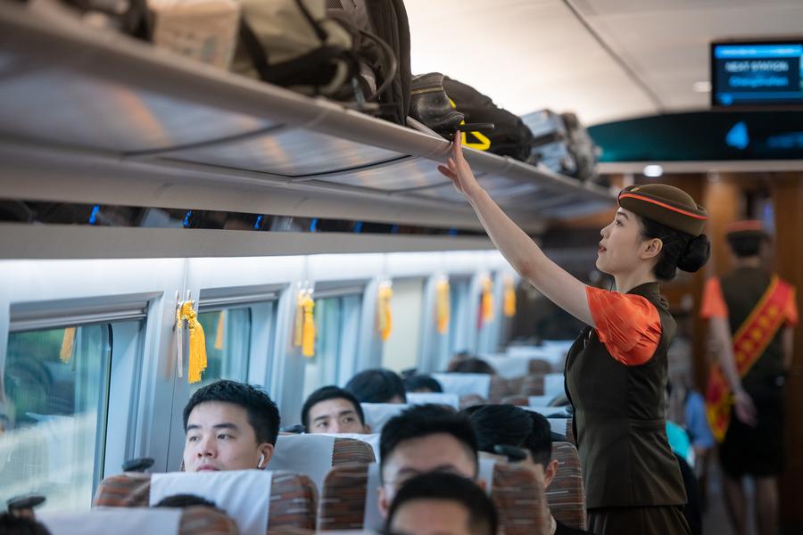 A train attendant checks the luggage rack onboard the G875 bullet train bound for Shenzhen on June 15, 2024. /Xinhua