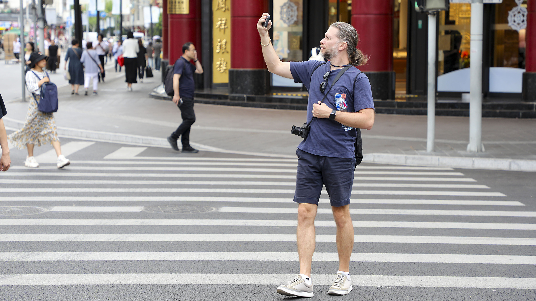 A foreign tourist takes a photo of his surroundings in east China's Shanghai, May 20, 2024. /CFP