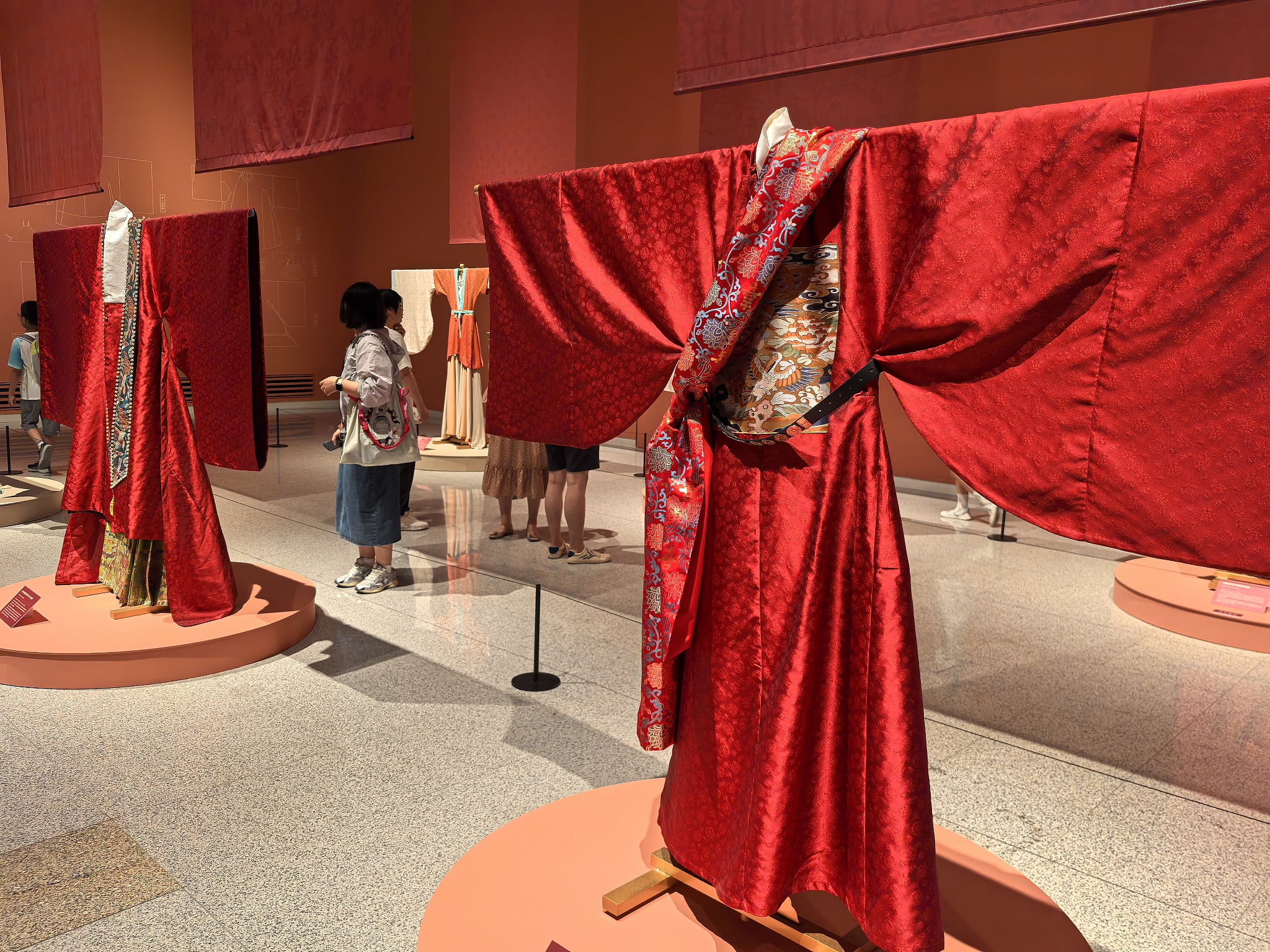 Visitors browse draped garments on display at the 