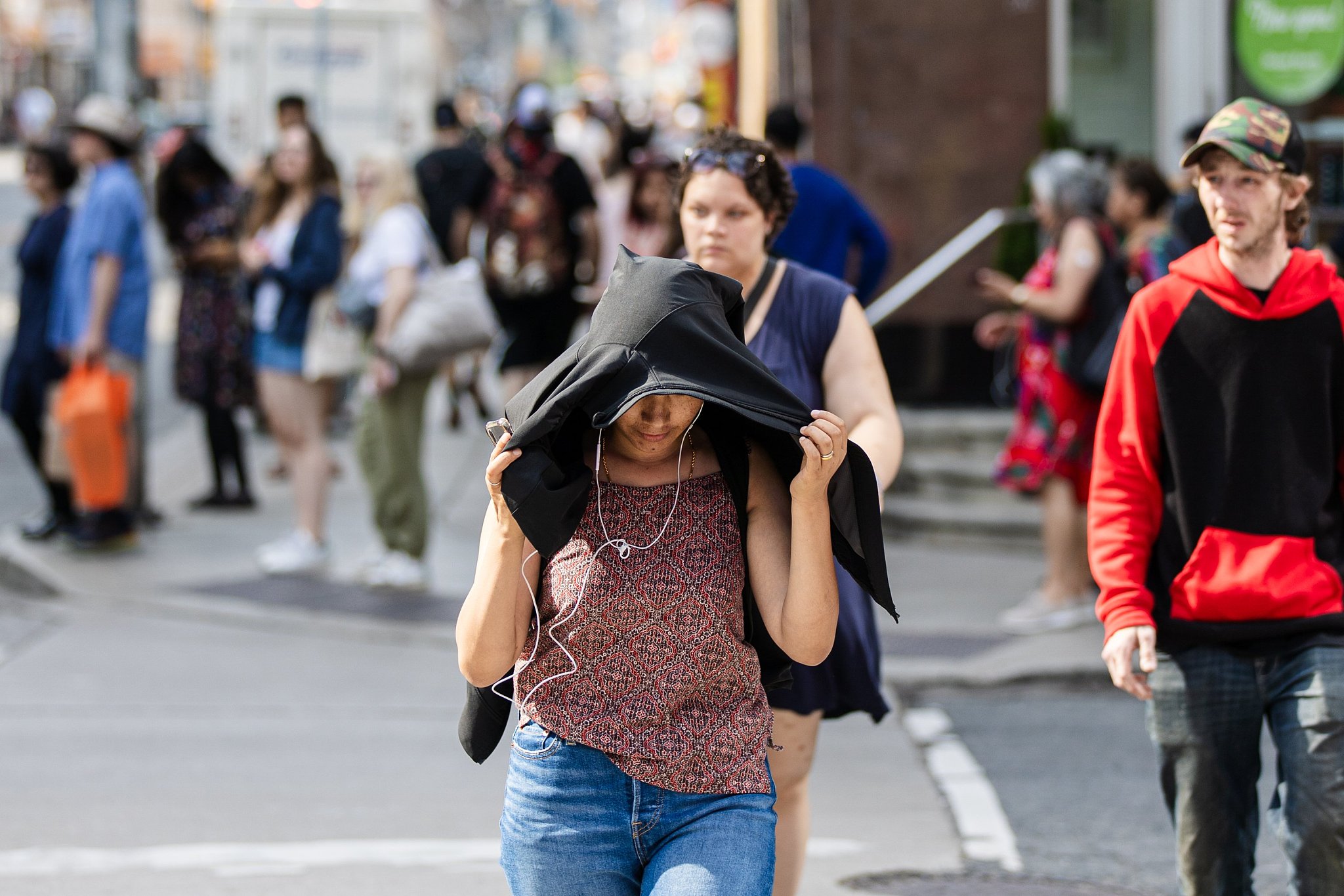A woman uses her coat to protect herself from the extreme heat in Toronto, Canada, June 18, 2024. /CFP