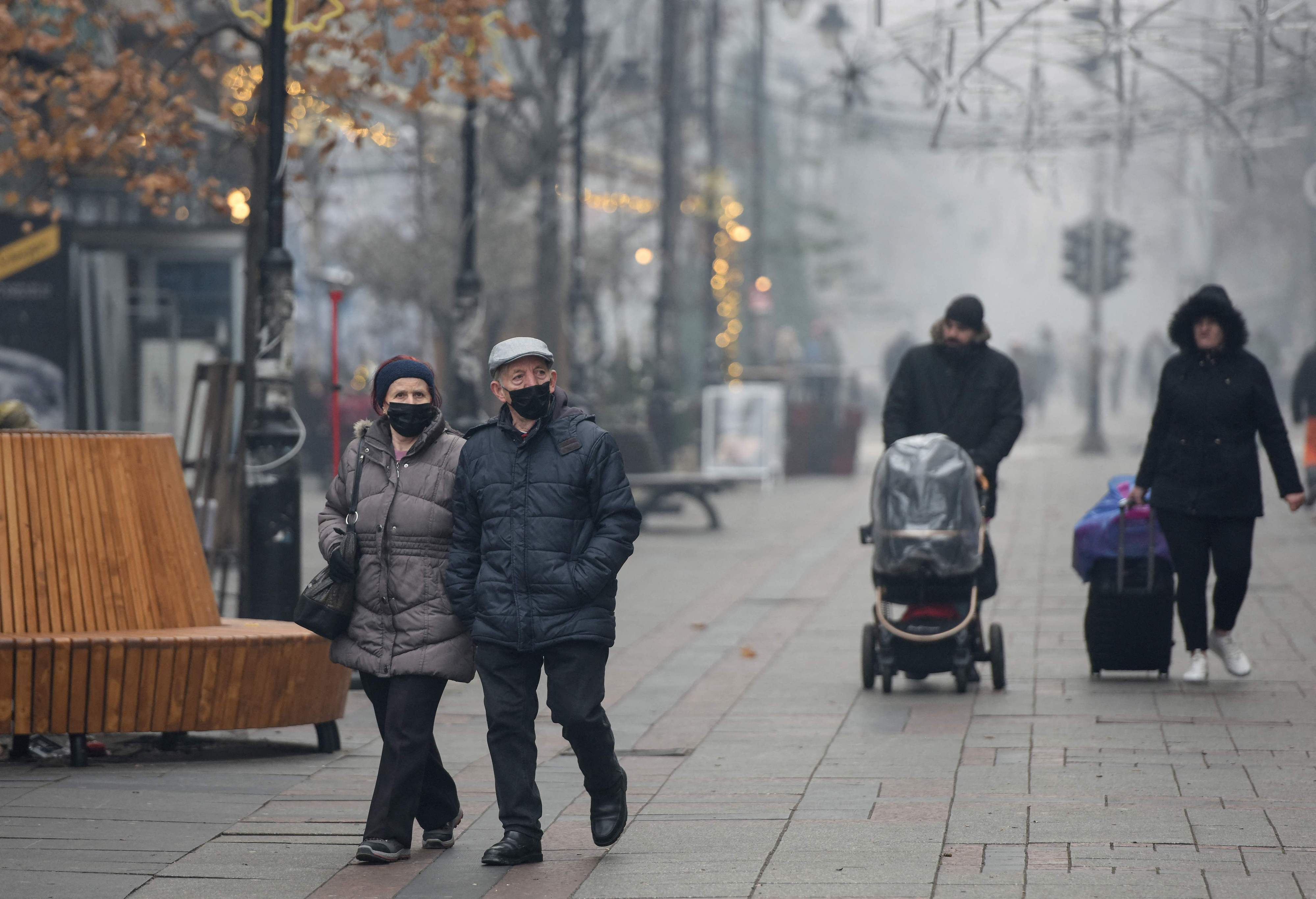 People wear protective masks while walking in a street amid heavy fog and air pollution in Skopje, North Macedonia, December 30, 2023. /CFP