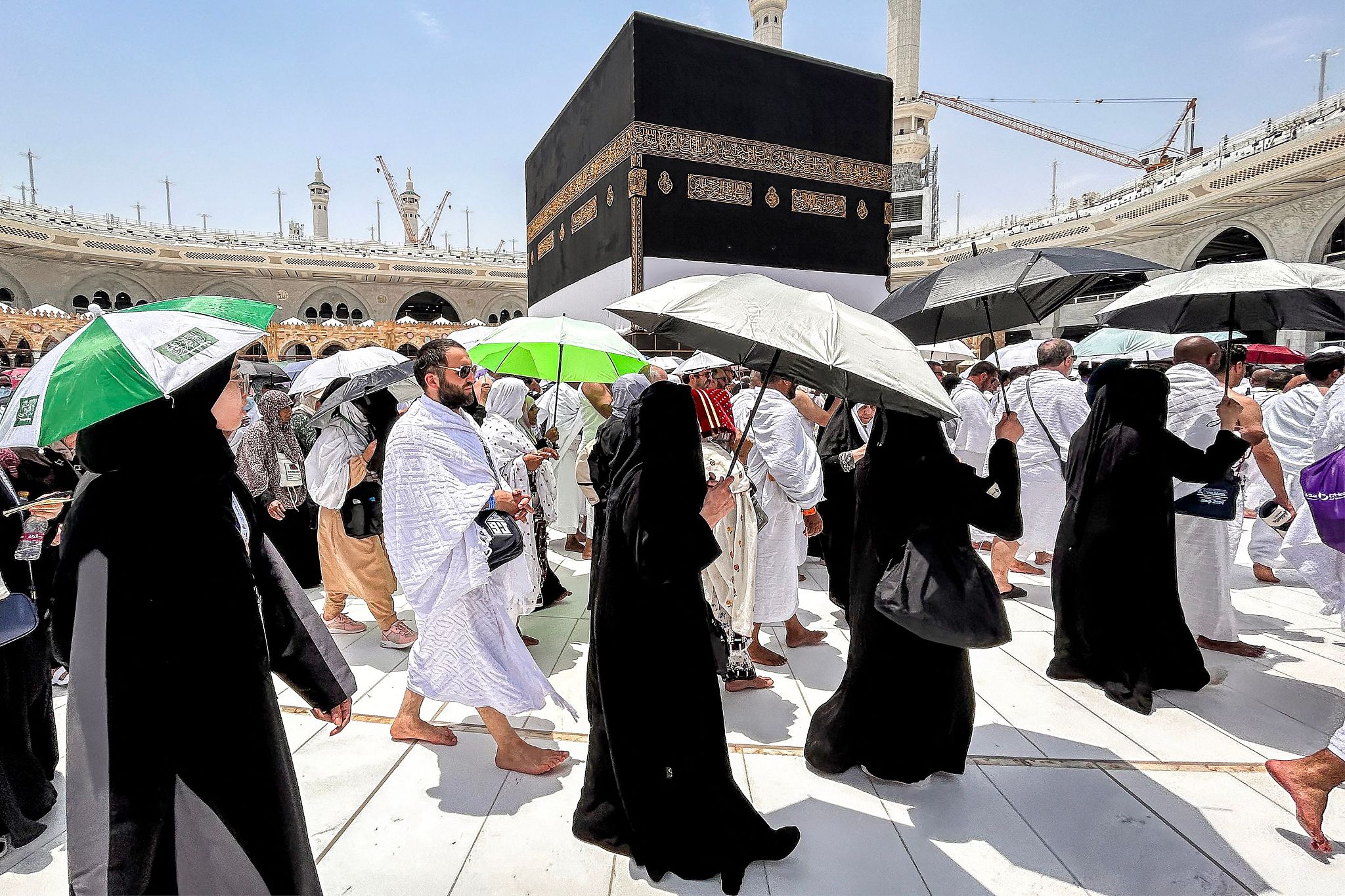 Devotees hold umbrellas to shield them from scorching heat as they walk around the Kaaba, Islam's holiest shrine, at the Grand Mosque in Saudi Arabia's holy city of Mecca, June 14, 2024. /CFP