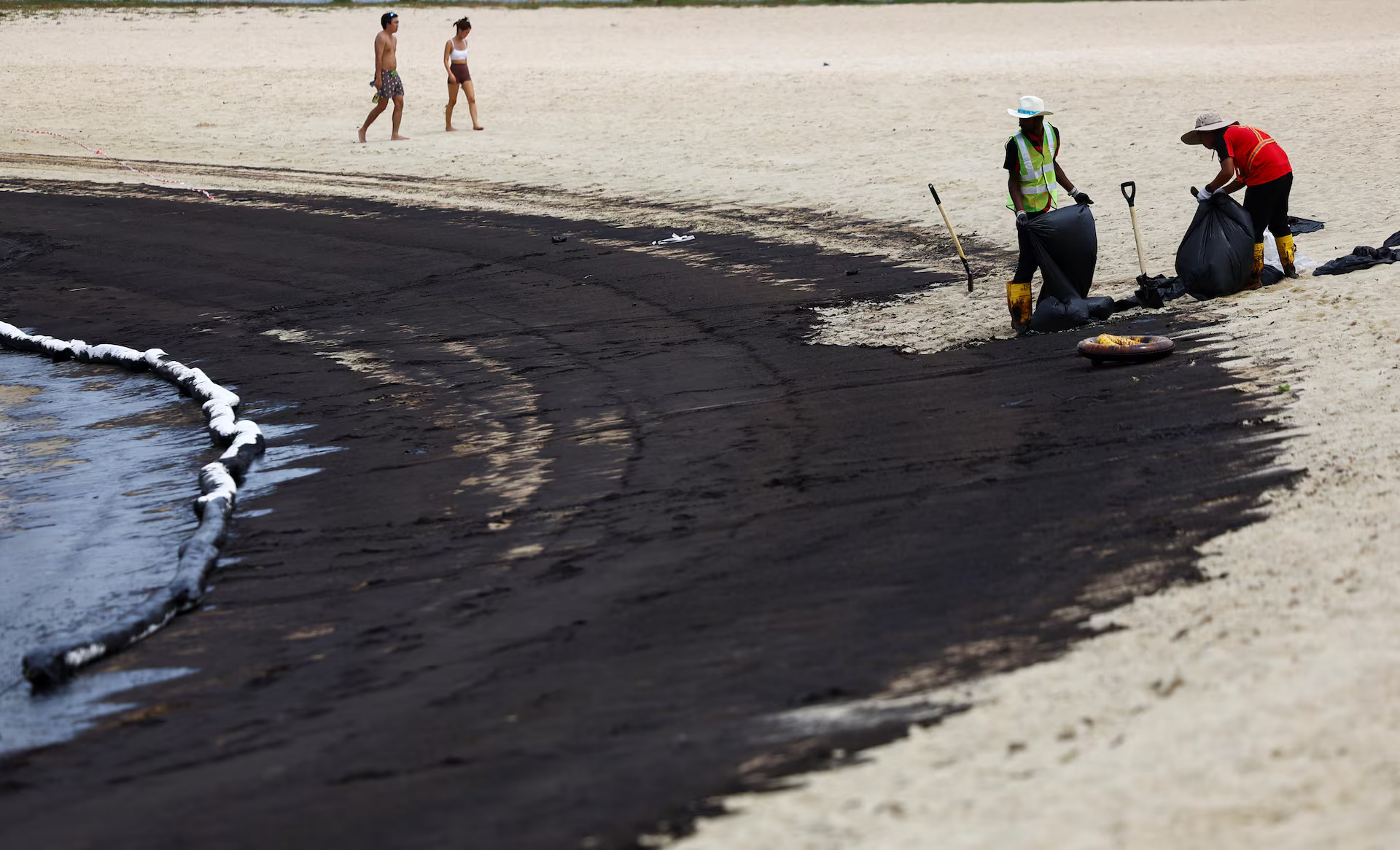Workers clean up a beach following an oil slick, at Tanjong Beach in Sentosa, Singapore, June 15, 2024. /Reuters