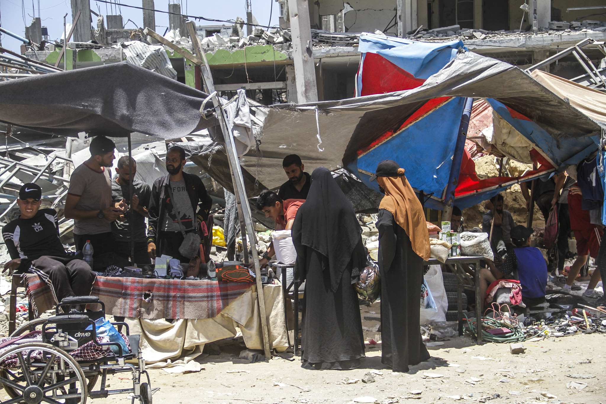 Palestinians shop at a market built among buildings, some of which are destroyed and the majority of which are heavily damaged and unusable as Palestinians are trying to survive at the Jabalia Refugee Camp in Gaza City, Gaza on June 20, 2024. /CFP