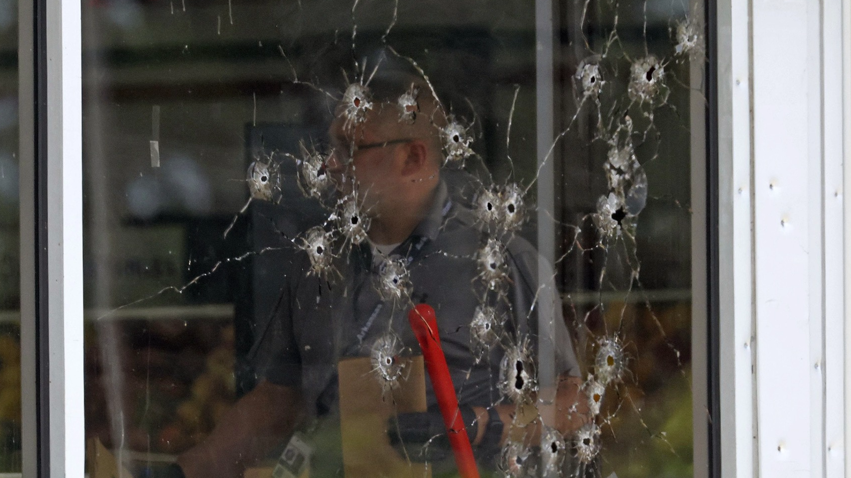 A front window damaged by bullets as law enforcement officers work the scene of a shooting at the Mad Butcher grocery store in Arkansas, the United States, June 21, 2024. /CFP
