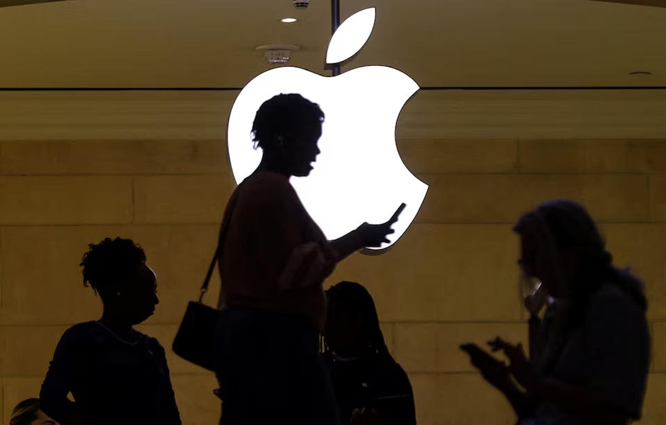 A woman uses an iPhone as she passes a lighted Apple logo at the Apple store at Grand Central Terminal in New York City, U.S., April 14, 2023. /Reuters