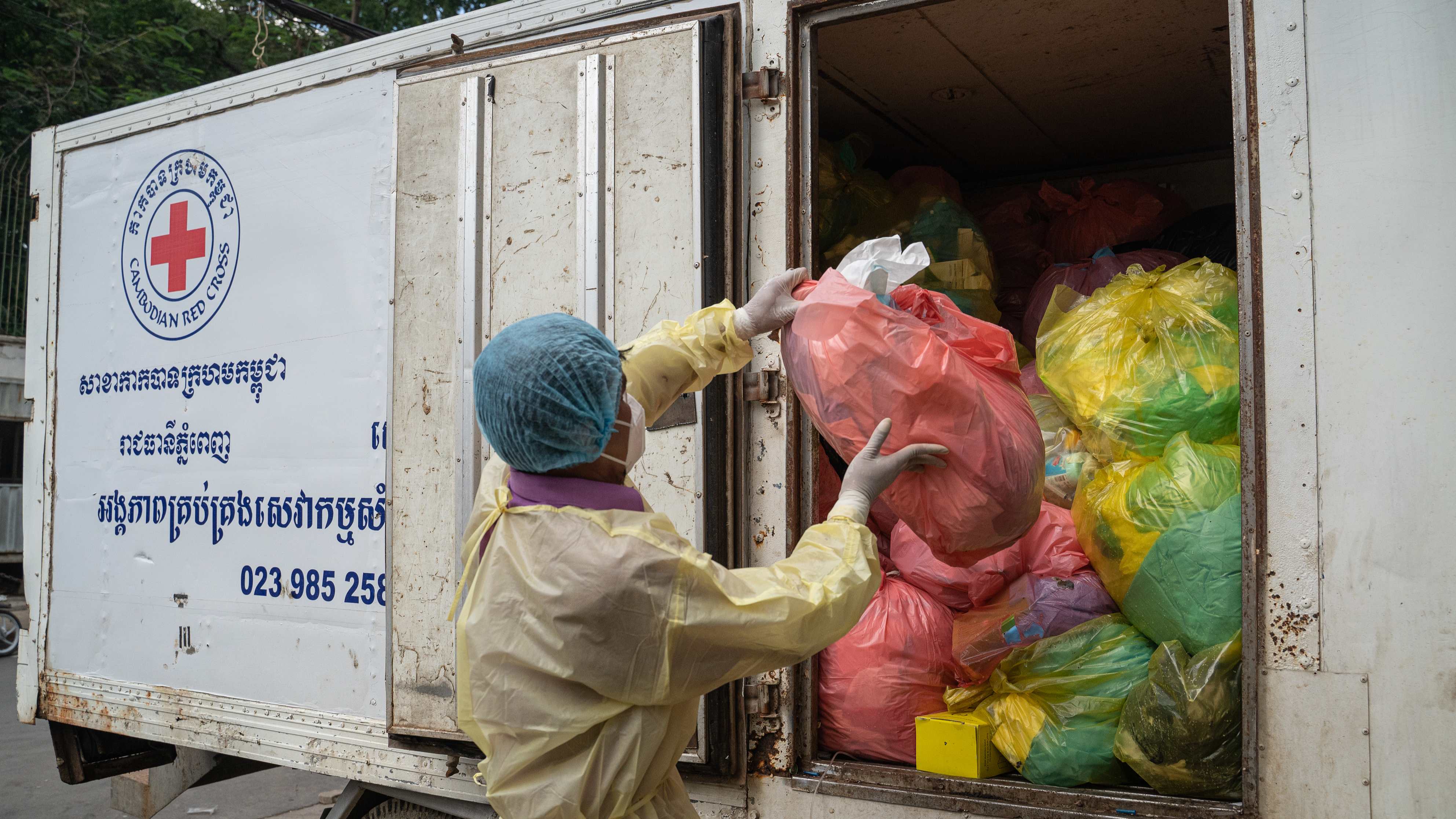 A worker tosses a bag of medical waste onto a medical waste collection van in Phnom Penh, Cambodia, October 22, 2021. /CFP