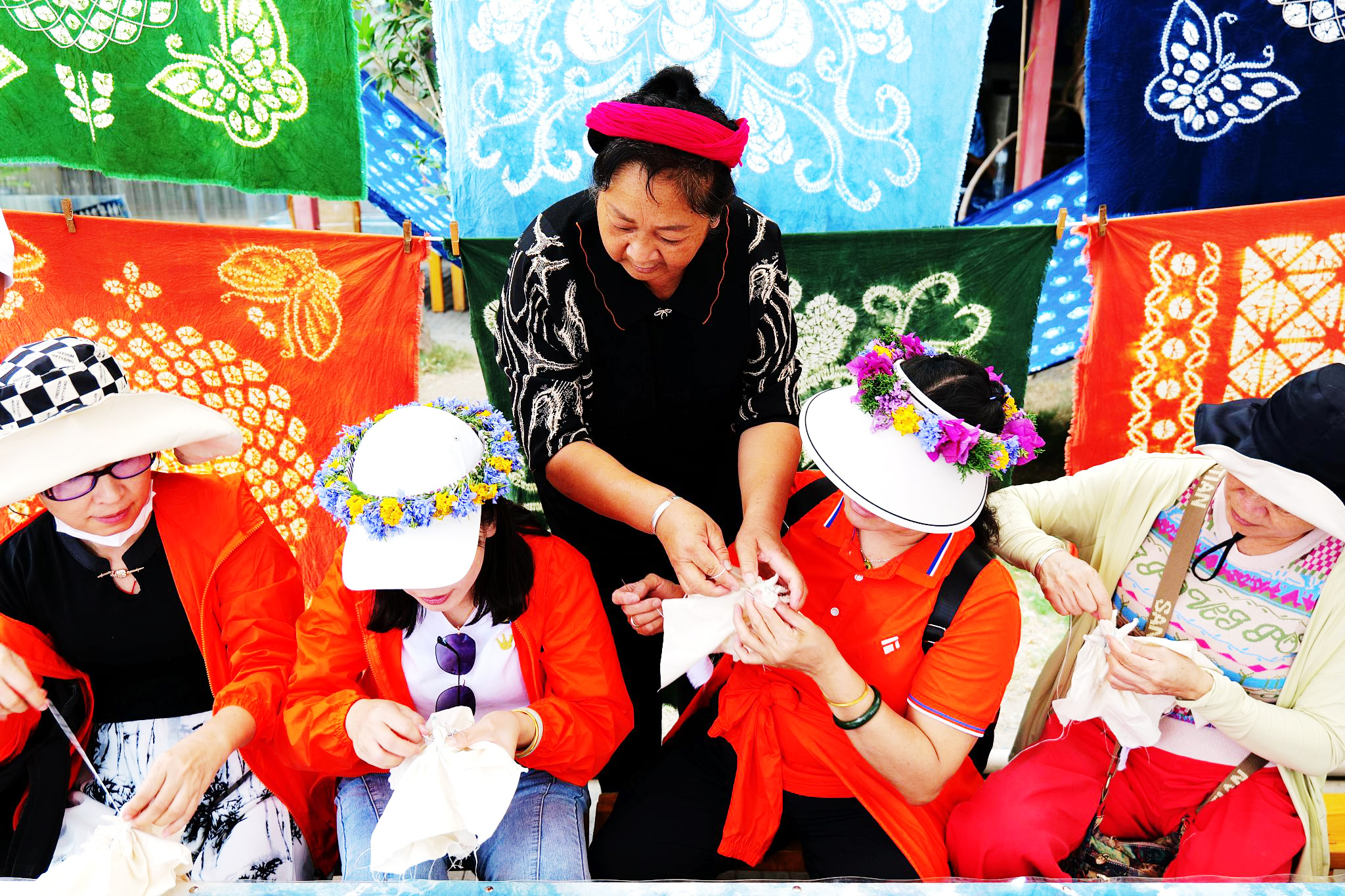 A local woman teaches tourists how to knot the cloth for tie-dyeing in Dali, Yunnan Province on June 22, 2024. /CFP