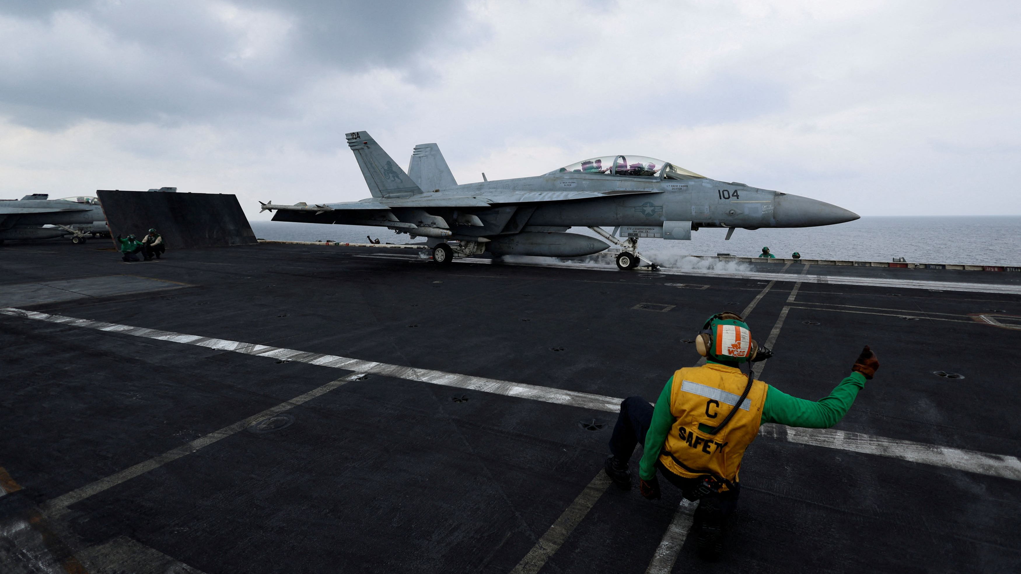 A flight operating crew member signals a F/A-18E Super Hornet fighter jet on the flight deck of the USS Dwight D. Eisenhower (CVN 69) aircraft carrier in Southern Red Sea, Middle East, February 13, 2024. /Reuters