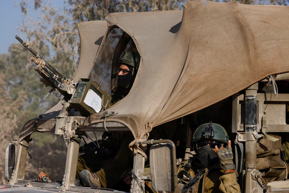 An Israeli soldier gestures while in a military vehicle, amid the Israel-Hamas conflict, near the Israel-Gaza border, in Israel, June 23, 2024. /Reuters