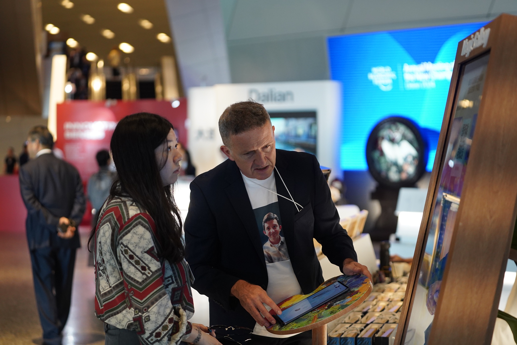 An exhibitor assisting a visitor at the Summer Davos 2024 venue in Dalian, Liaoning Province, China, June 25, 2024. /CFP