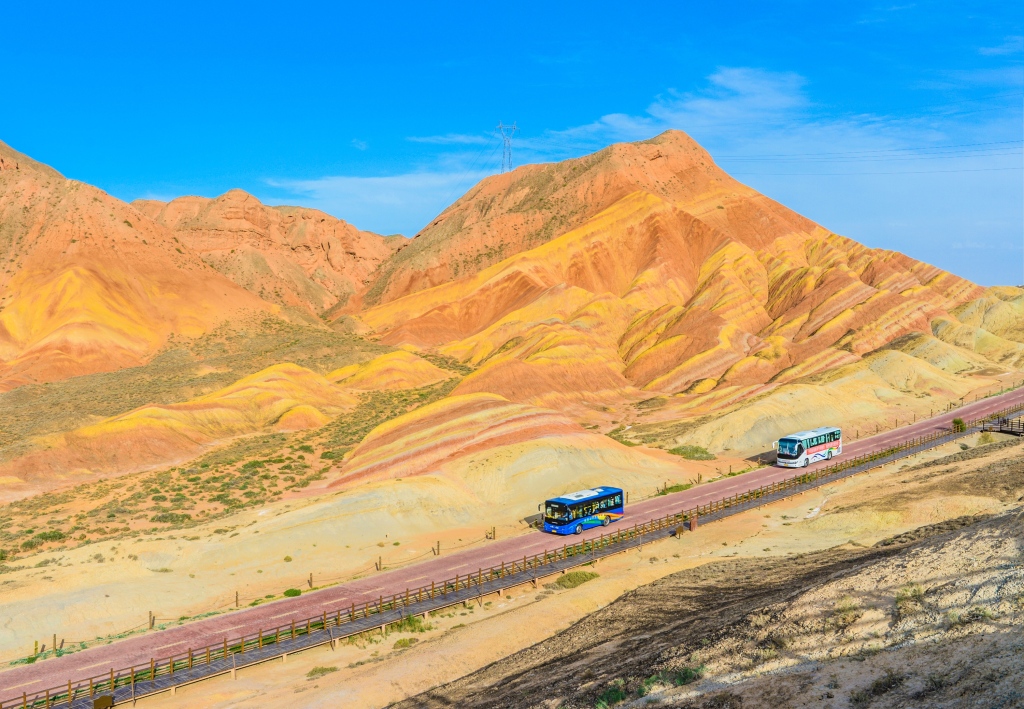 Busses pass through the Colorful Danxia Scenic Spot in Zhangye, Gansu on June 25, 2024. /CFP