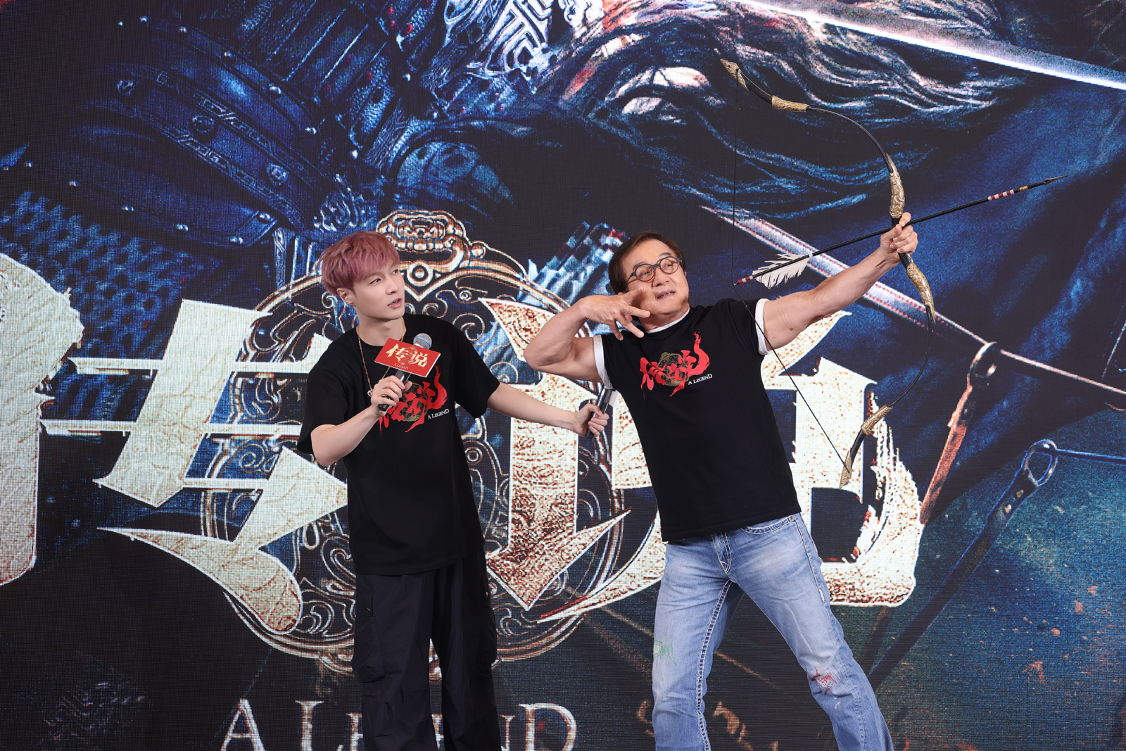 Jackie Chan (right) practices the use of the bow and arrow along with his co-star Lay Zhang, (left) at a press event on June 25, 2024, in Beijing. /Photo provided to CGTN