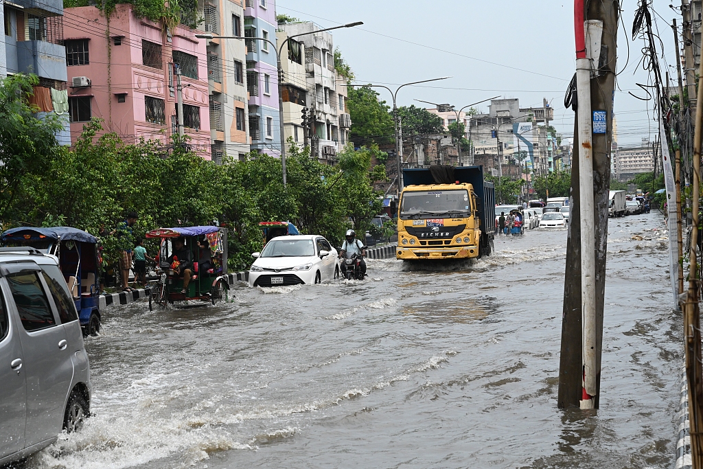 Vehicles and rickshaws try to drive through waterlogged streets caused by heavy monsoon rainfalls in Dhaka, Bangladesh, June 26, 2024. /CFP