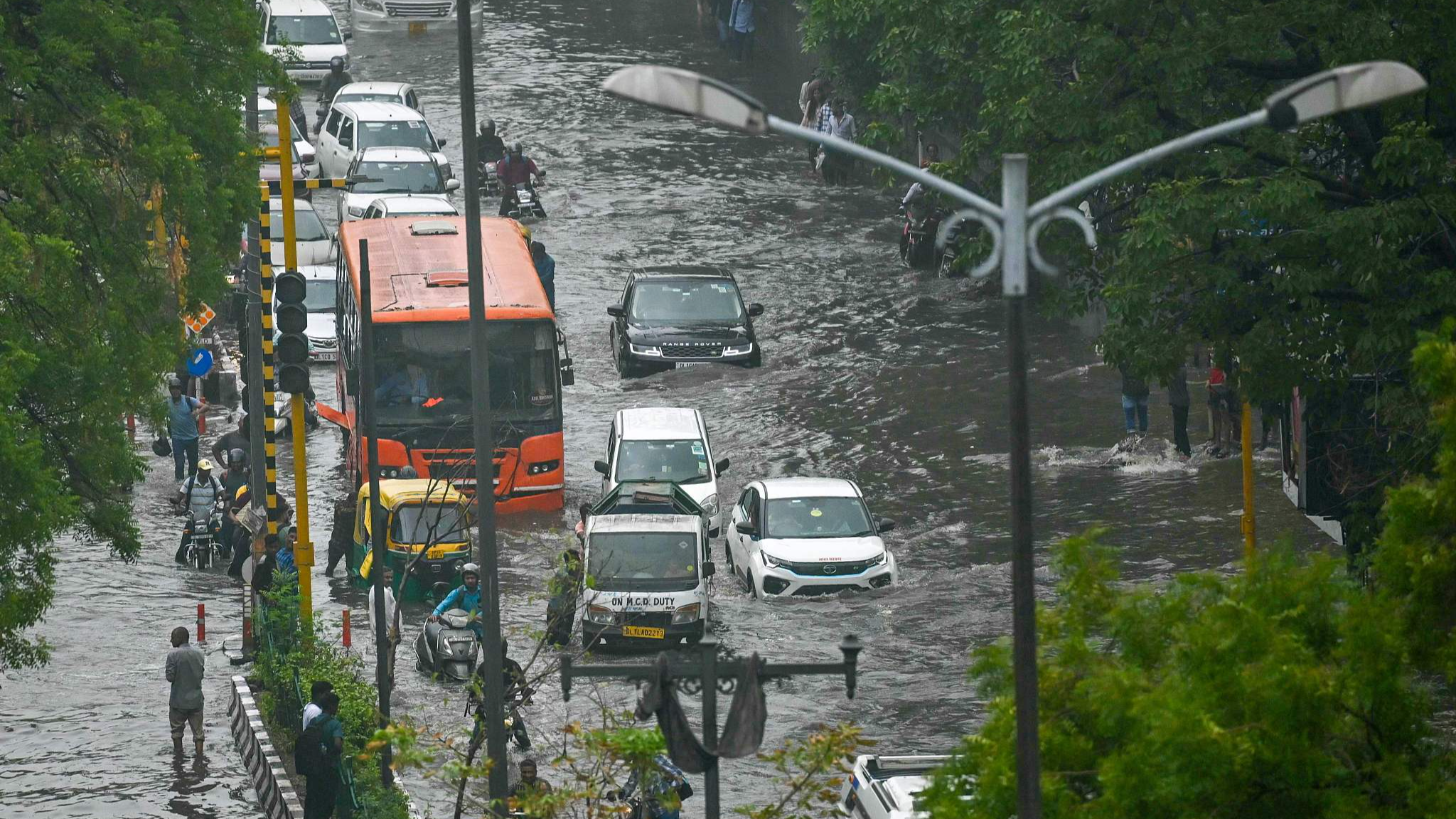 Vehicles and commuters wade through flooded streets after heavy rains in New Delhi, India, June 28, 2024. /CFP