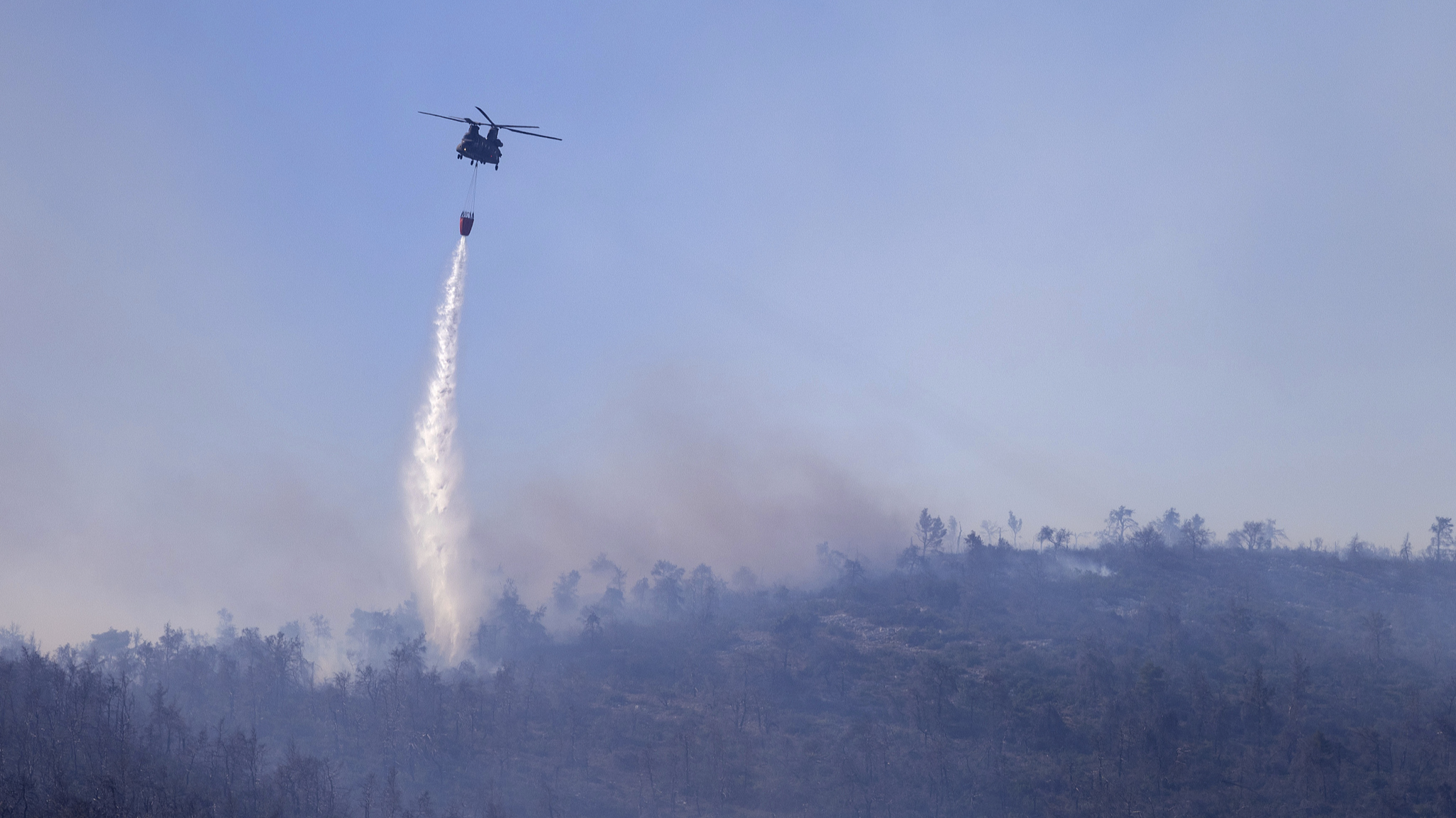 A helicopter throws water over a wildfire near Katsimidi area, on Mount Parnitha, north of Athens, Greece, June 29, 2024. /CFP