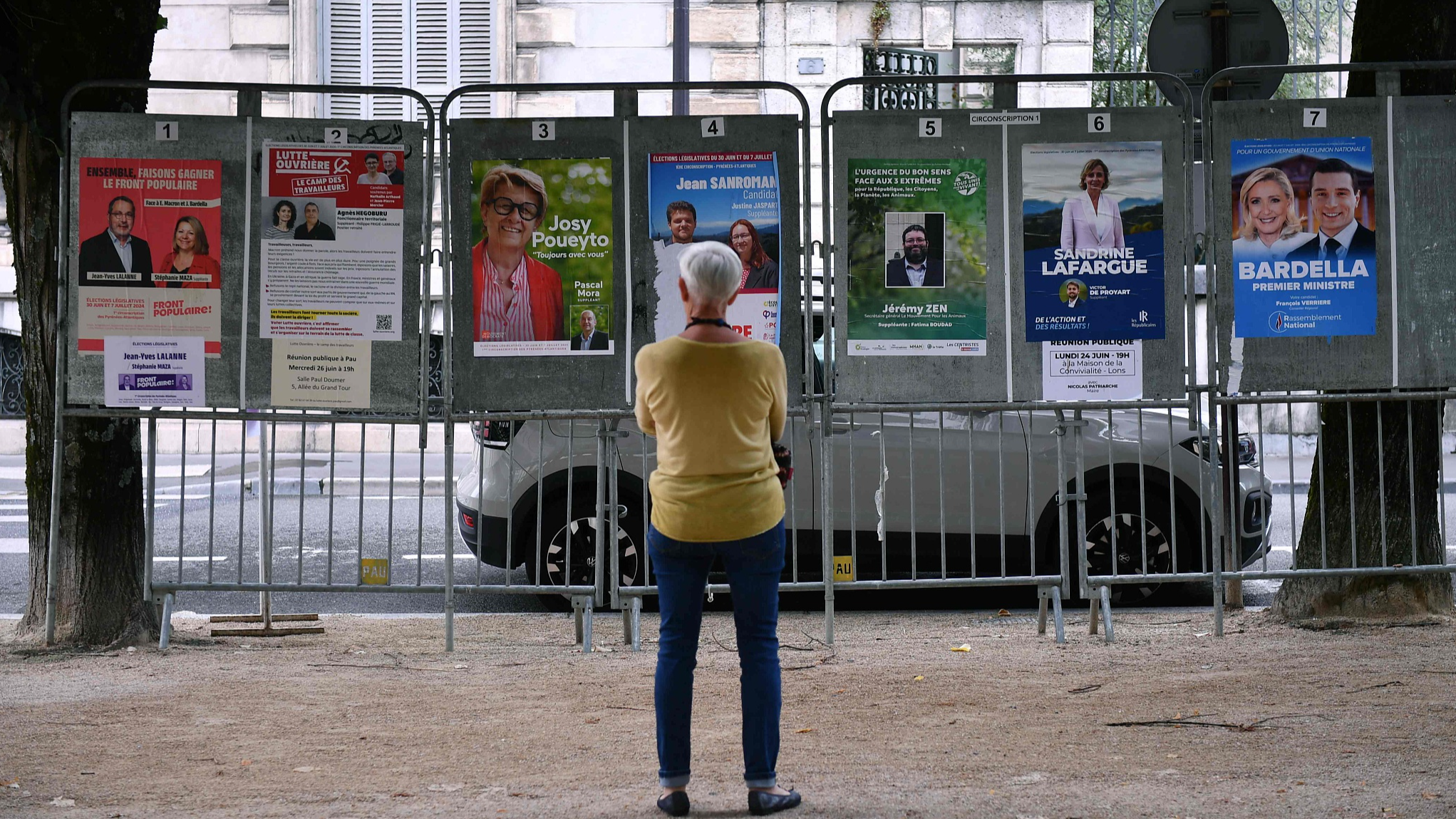 A woman looks at election posters next to a polling station during the first round of parliamentary elections in Pau, south-western France, June 30, 2024. /CFP