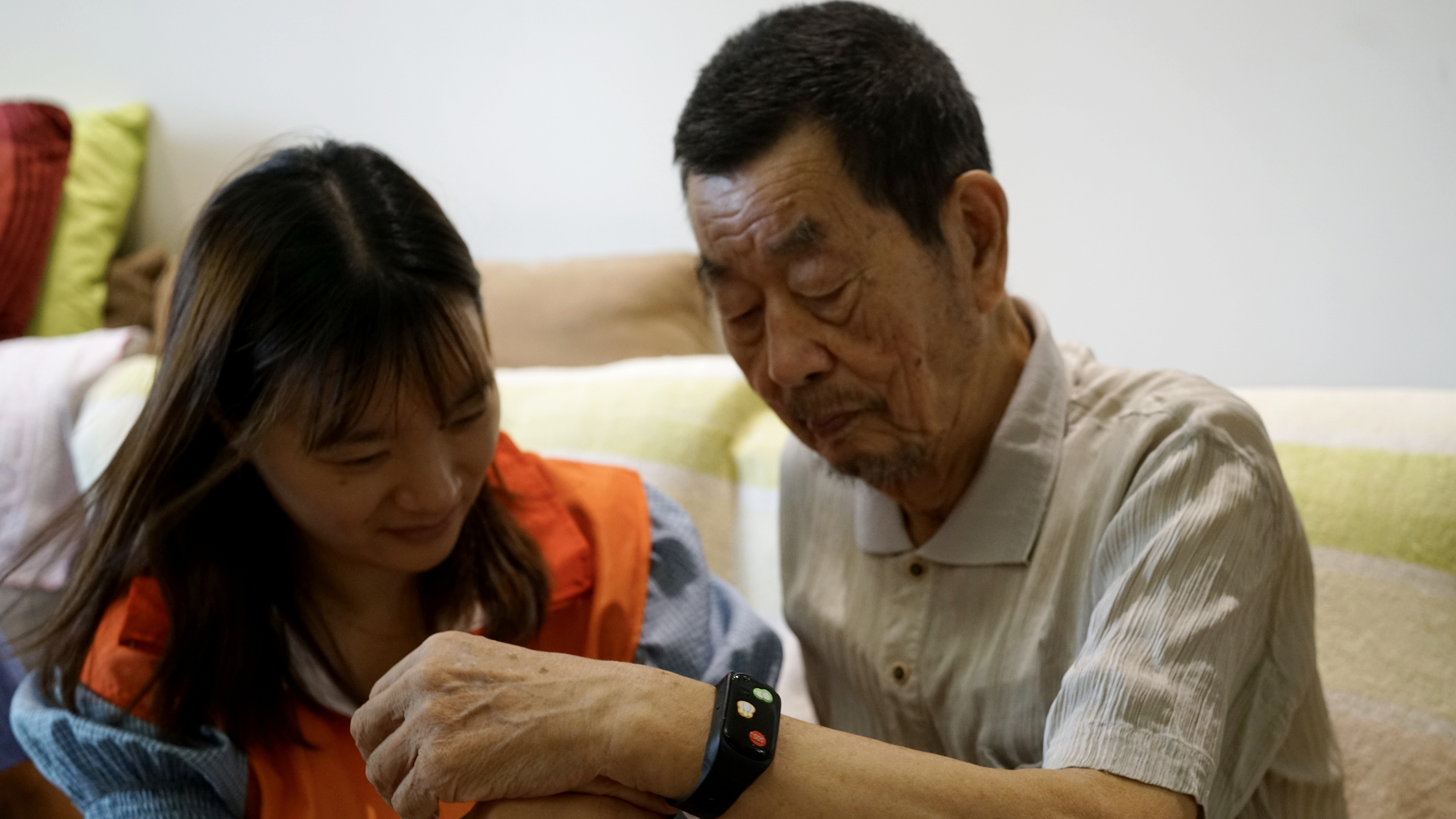 Zhang Yubei, 87, receives a smart bracelet from a community worker in Suzhou, east China's Jiangsu Province, August 11, 2023. /CFP